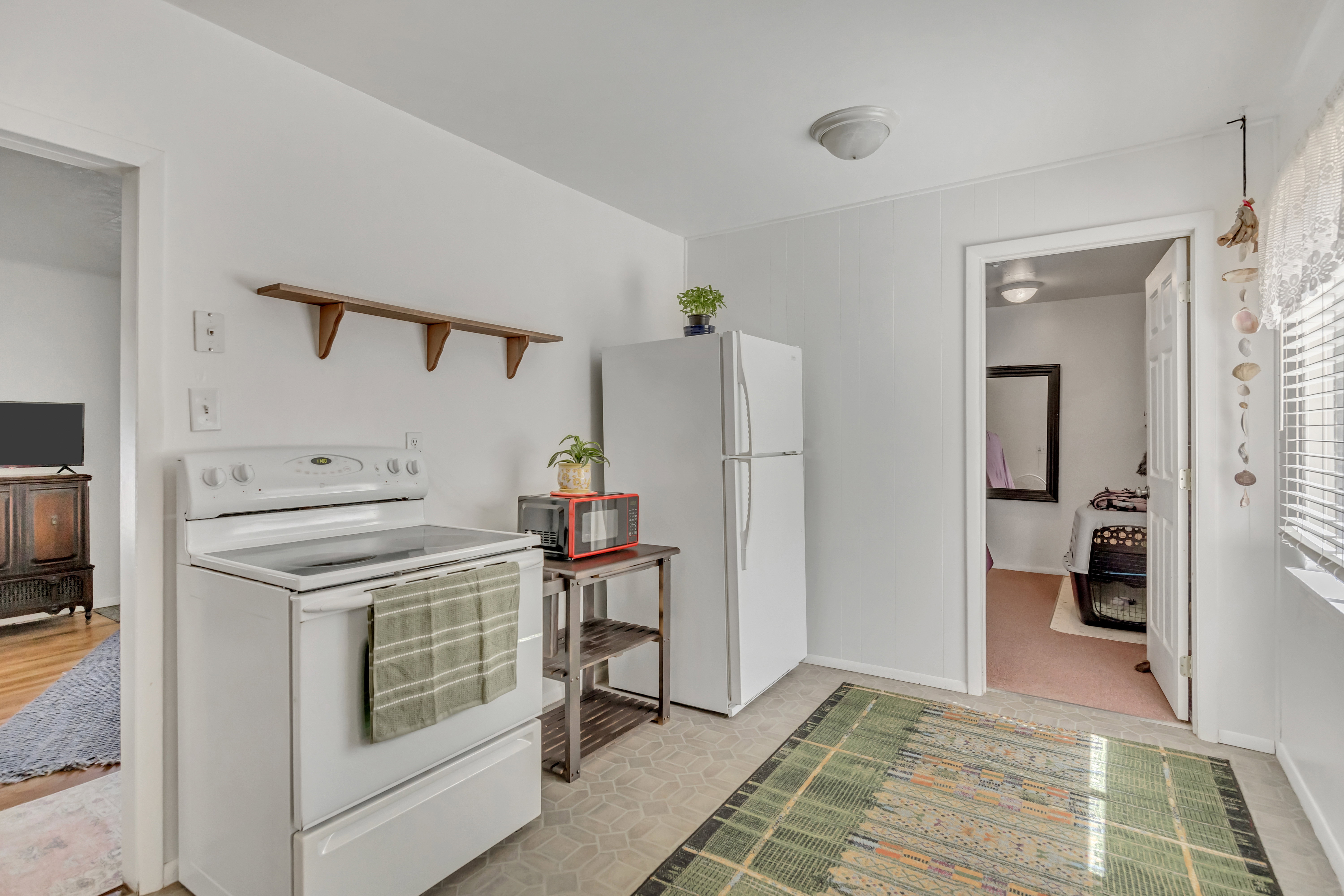 Kitchen featuring a white electric range, white refrigerator, and wood-finish open shelving