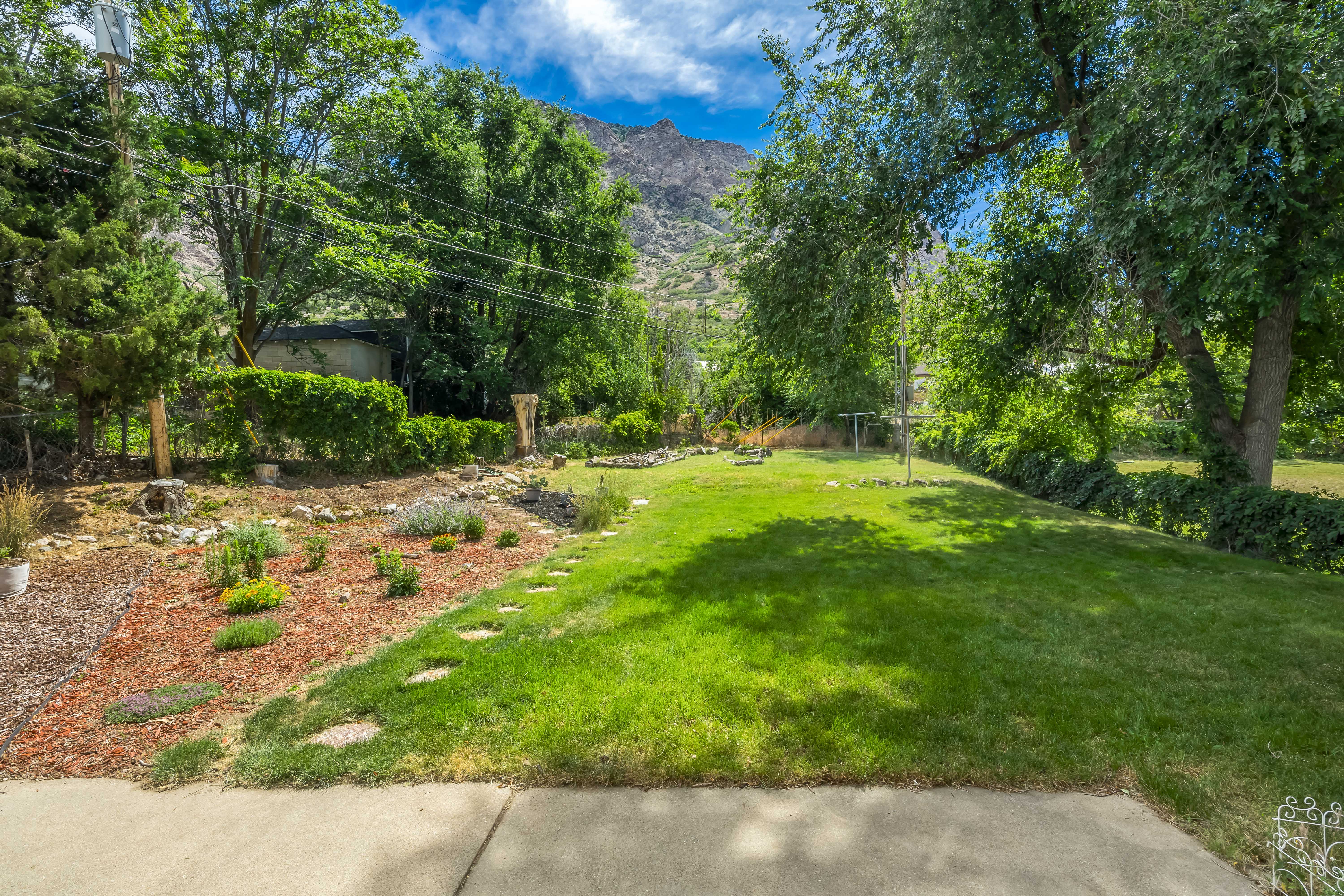 Expansive green lawn with stepping stones leading to a mulched garden bed
