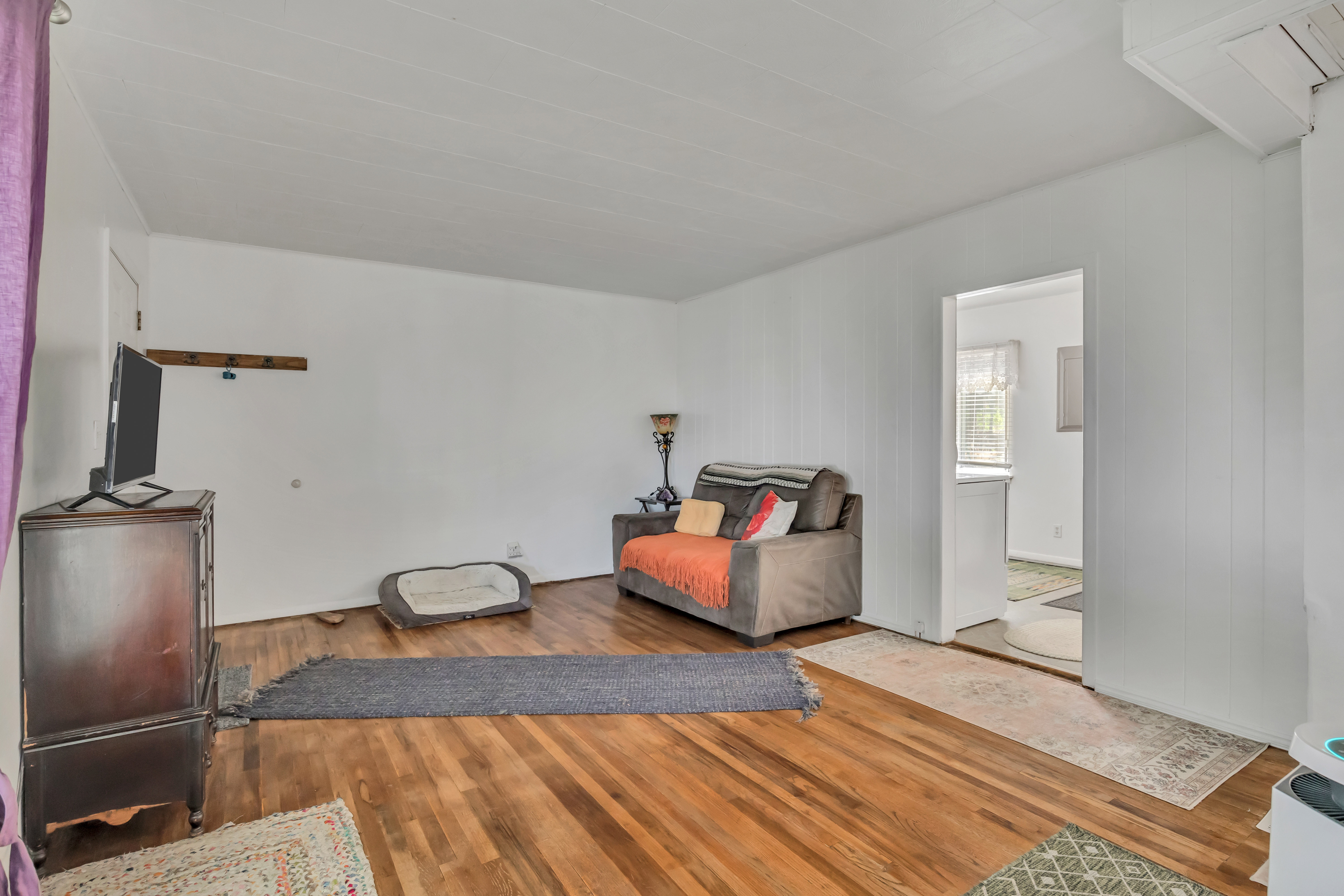 Spacious interior featuring wood-finish flooring, white paneled walls, and a white ceiling
