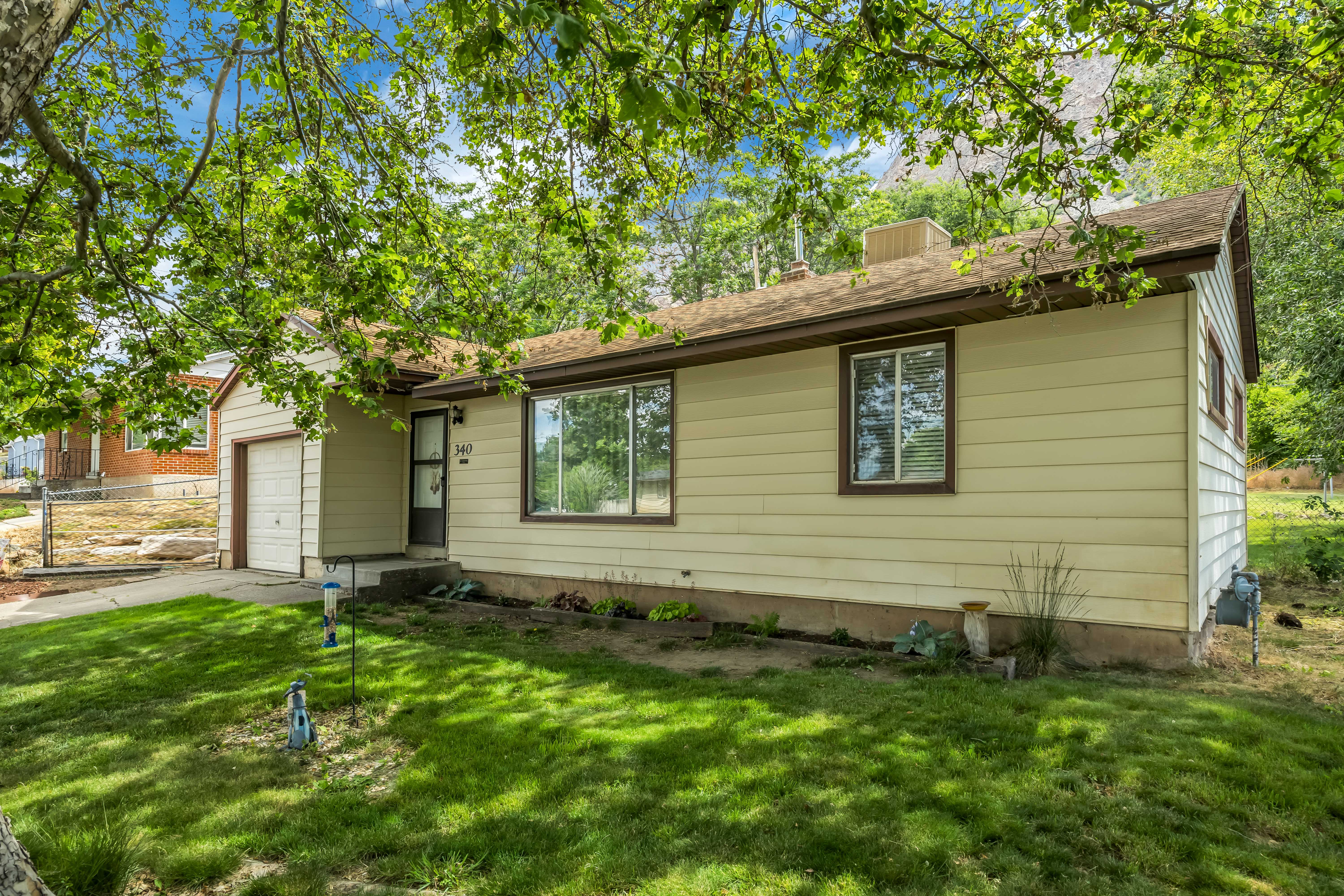 Ranch-style exterior with light-colored siding, a brown shingled roof, and a single-car garage