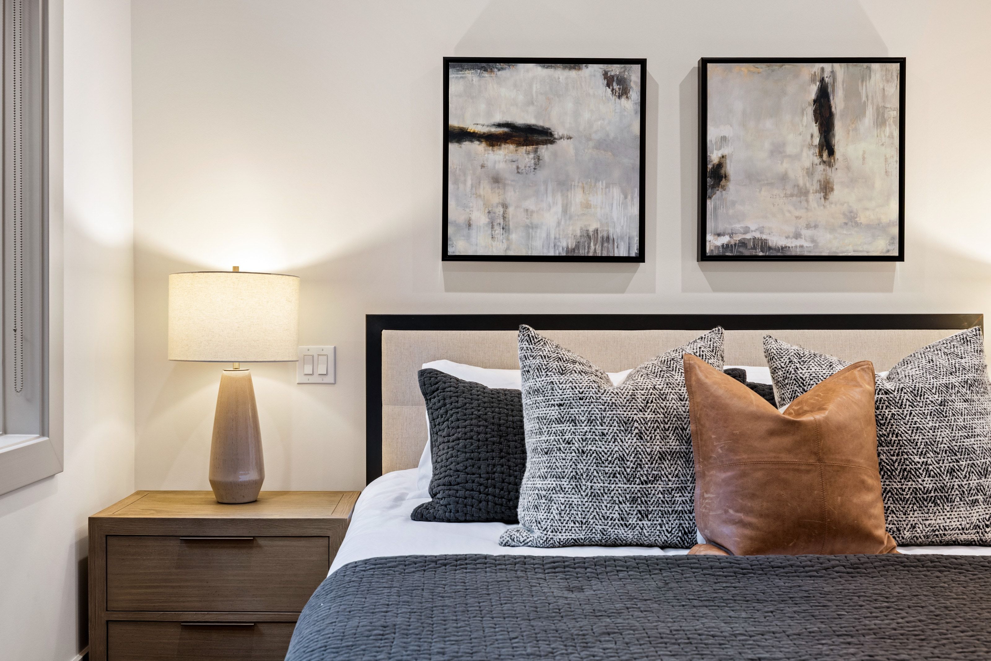Upholstered headboard with black trim, flanked by a wood-finish nightstand featuring two drawers