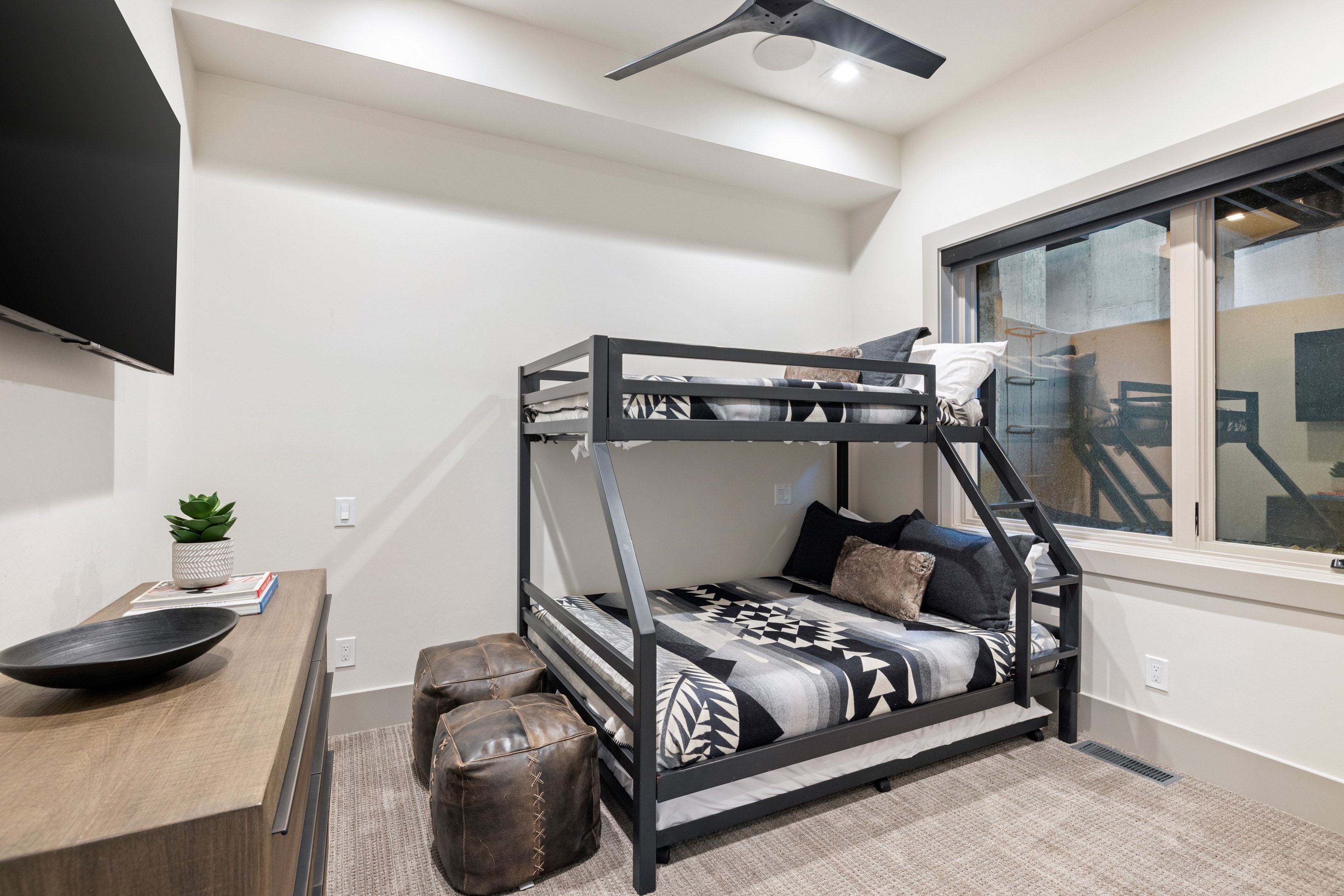 Bunk bed frame with integrated ladder, a large window, a ceiling fan, and recessed lighting