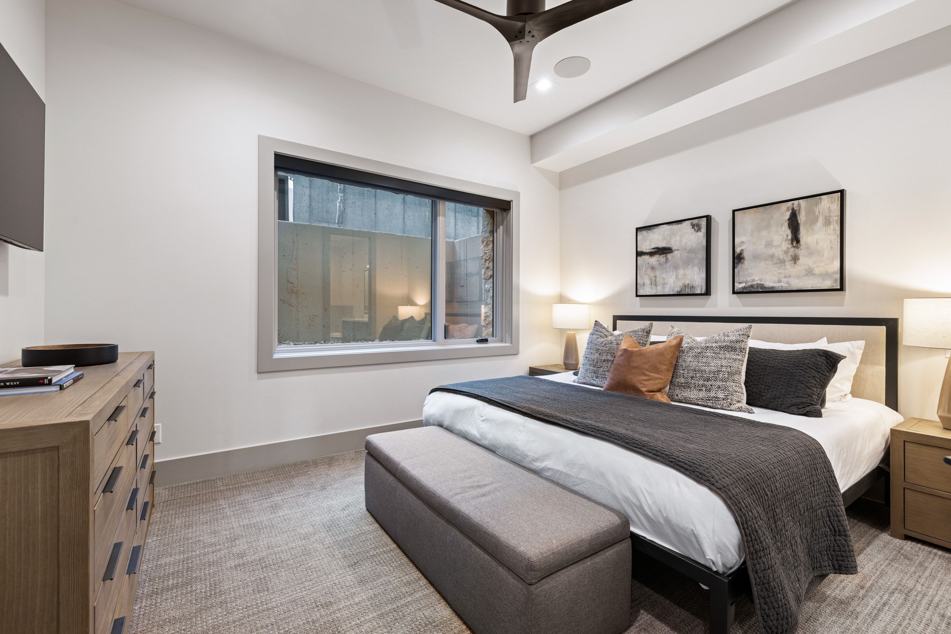 Recessed lighting and a modern ceiling fan illuminate this space featuring a large window, a neutral color palette, and textured carpeting