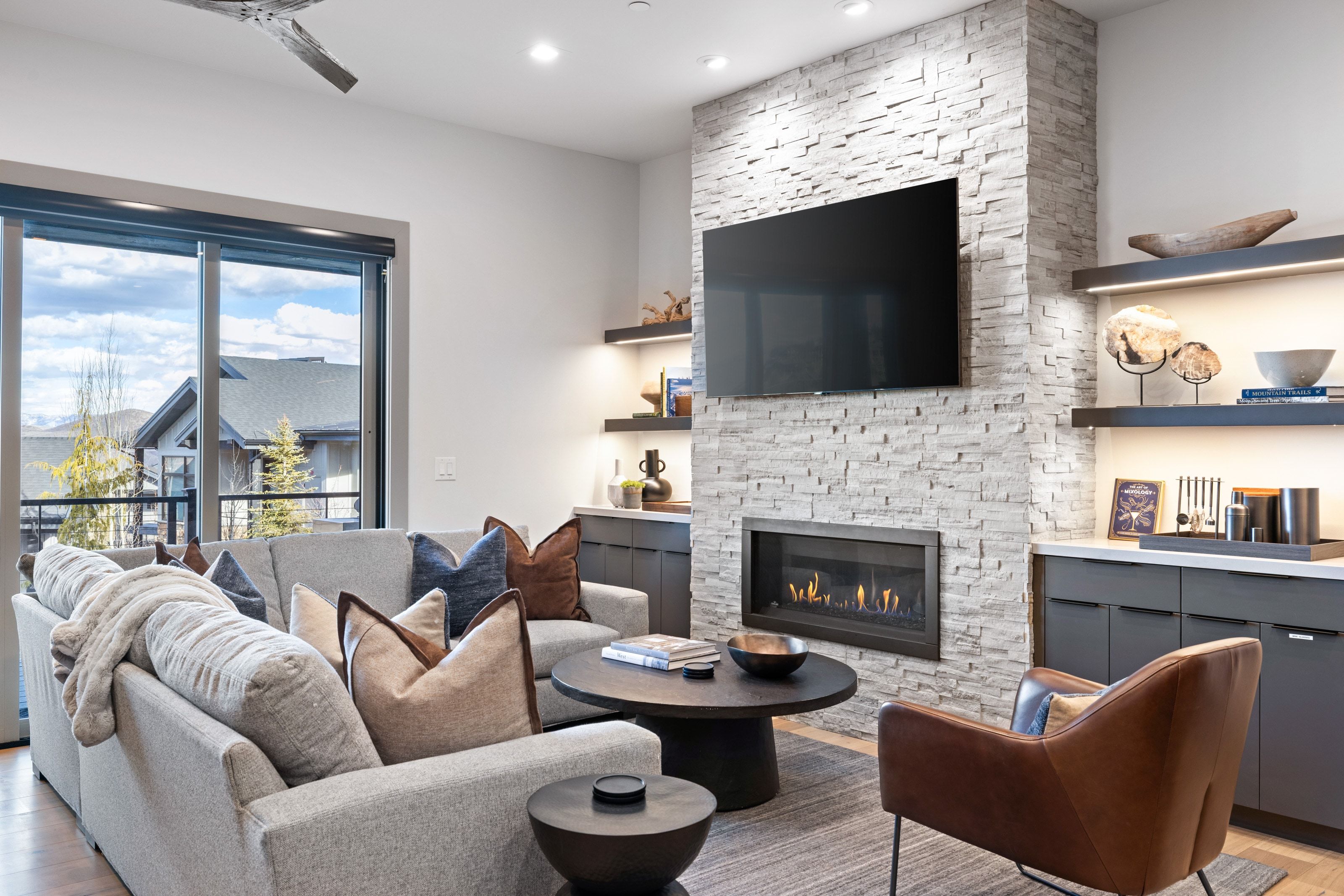 Living area featuring a floor-to-ceiling stacked stone fireplace with a built-in linear gas fireplace