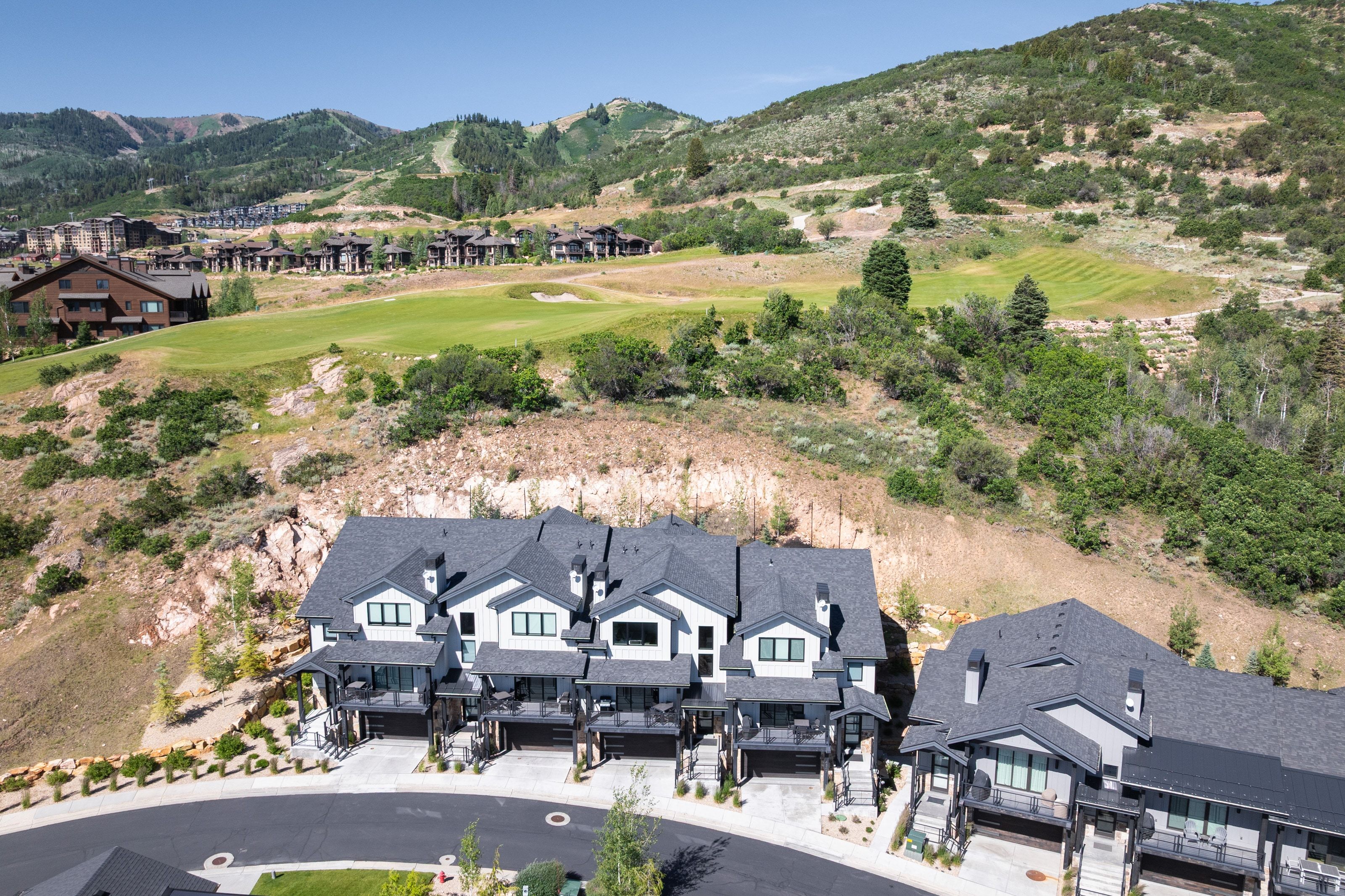 Contemporary multi-level townhomes with dark gray roofs, light-colored siding, and integrated garages