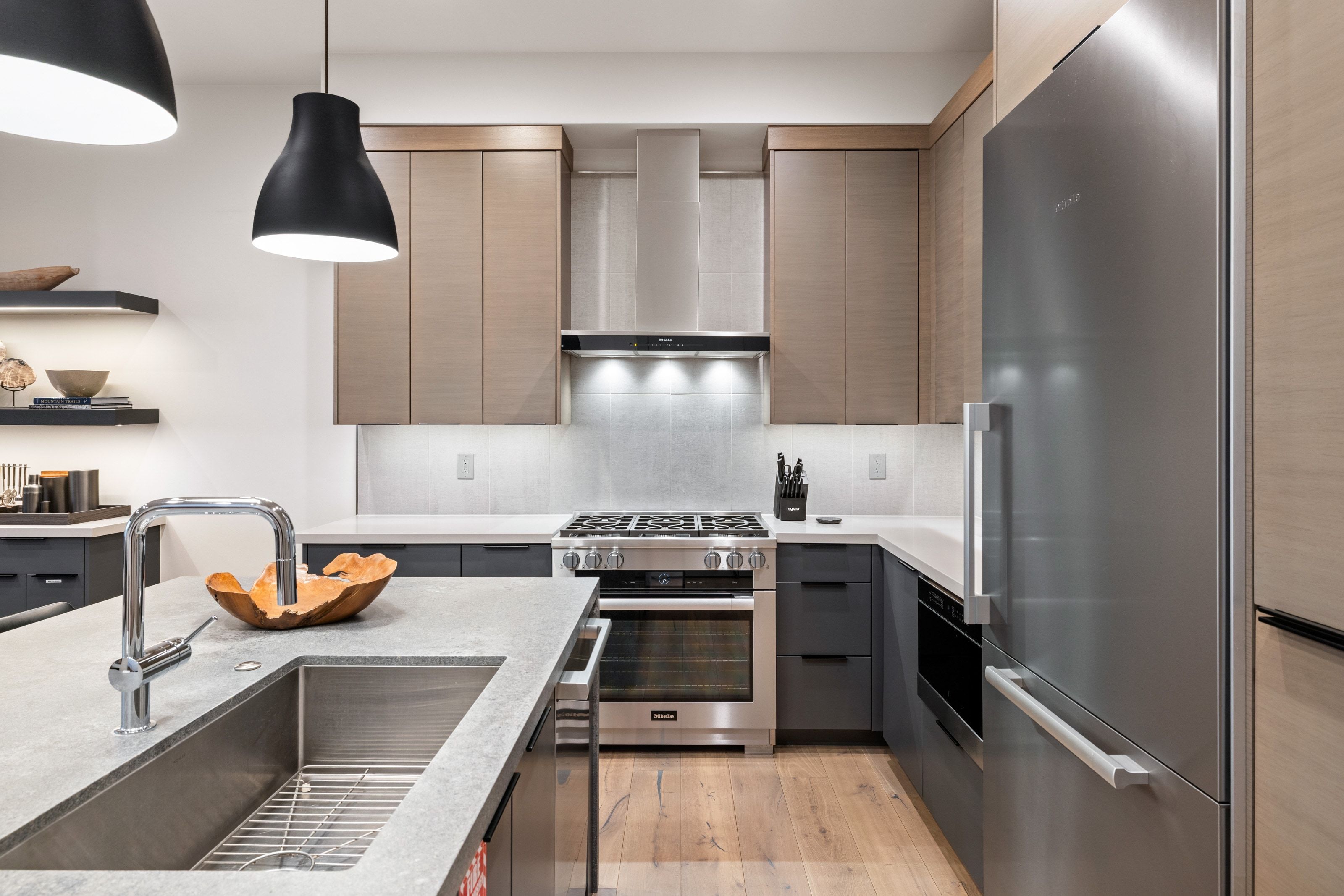 Contemporary kitchen featuring light wood-finish upper cabinetry, contrasting dark lower cabinetry, and light-toned countertops
