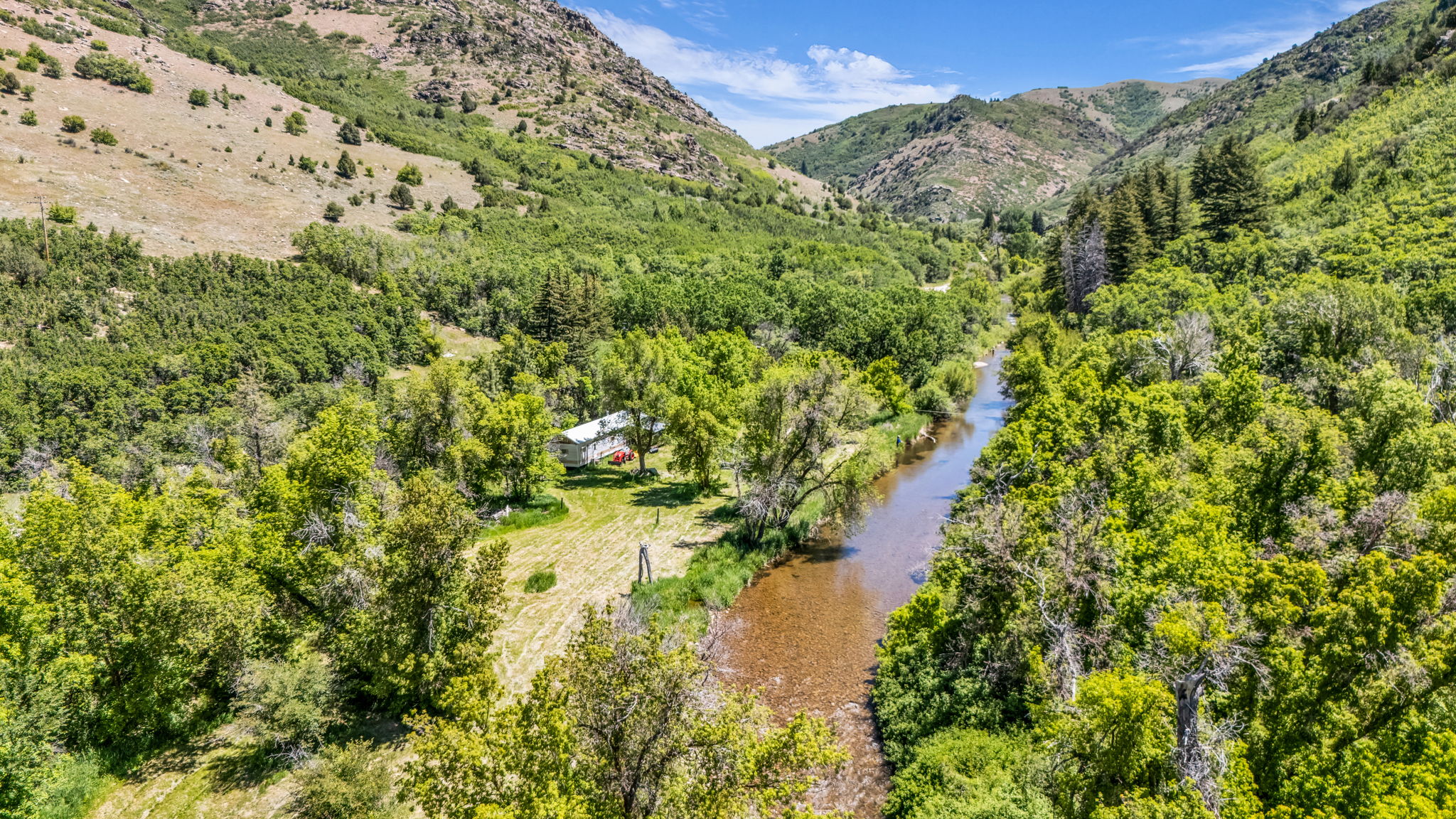 Expansive natural landscape featuring a river and surrounding green foliage, with a single-story residence visible in the distance