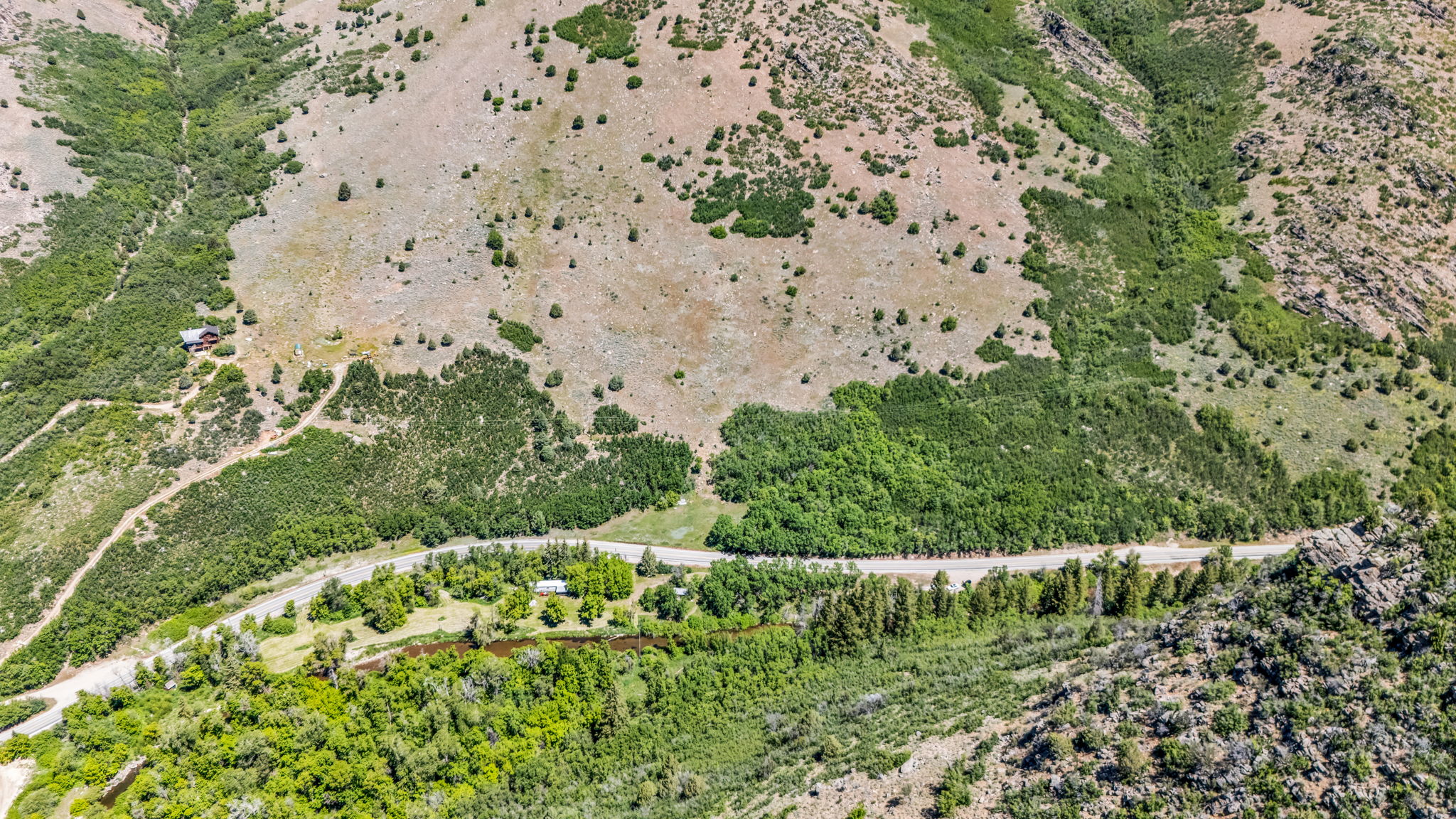 Aerial perspective showcasing a mountain landscape with a visible road and a river