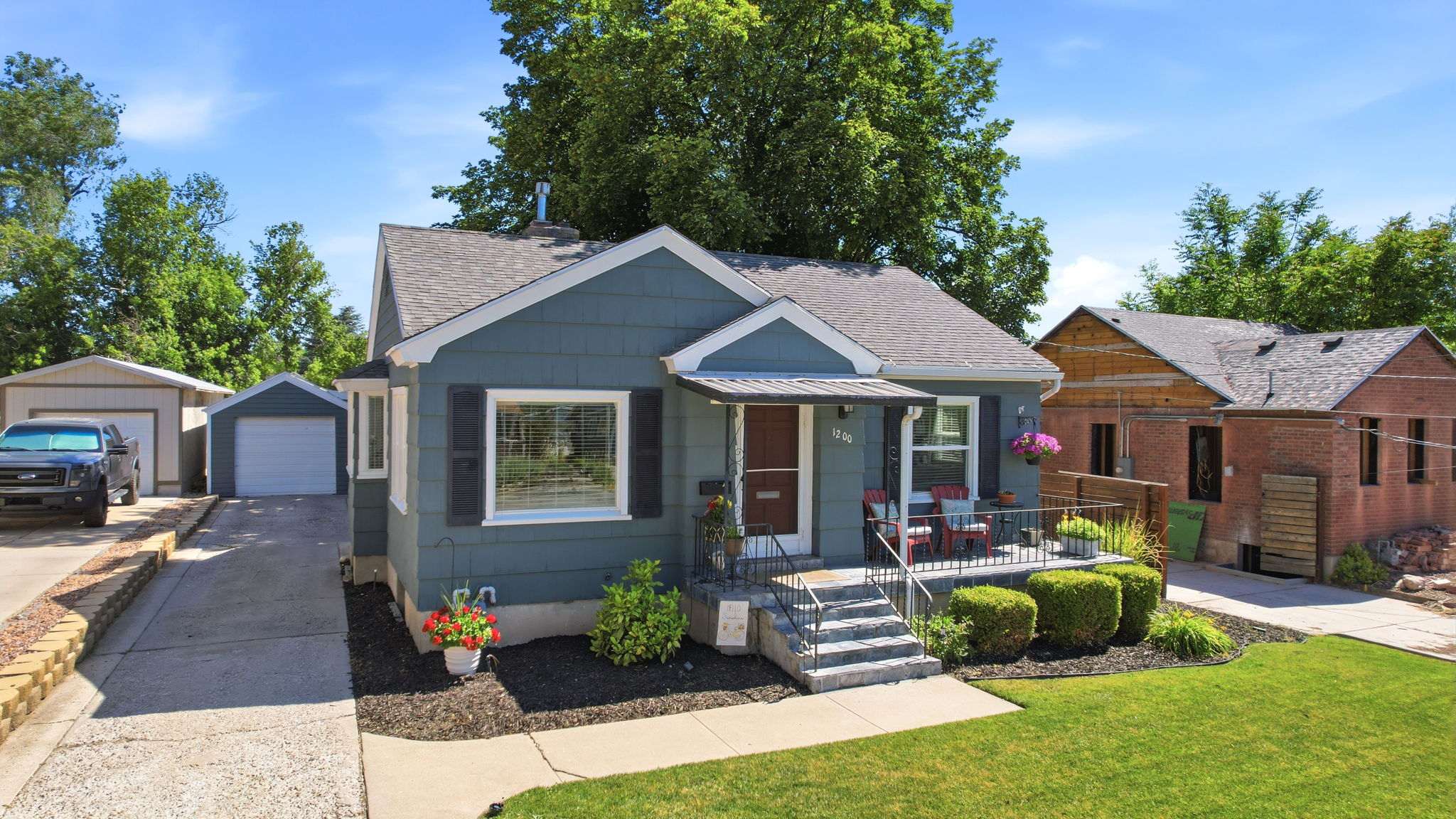 Charming bungalow featuring a covered front porch, concrete steps with wrought iron railing, and a manicured lawn