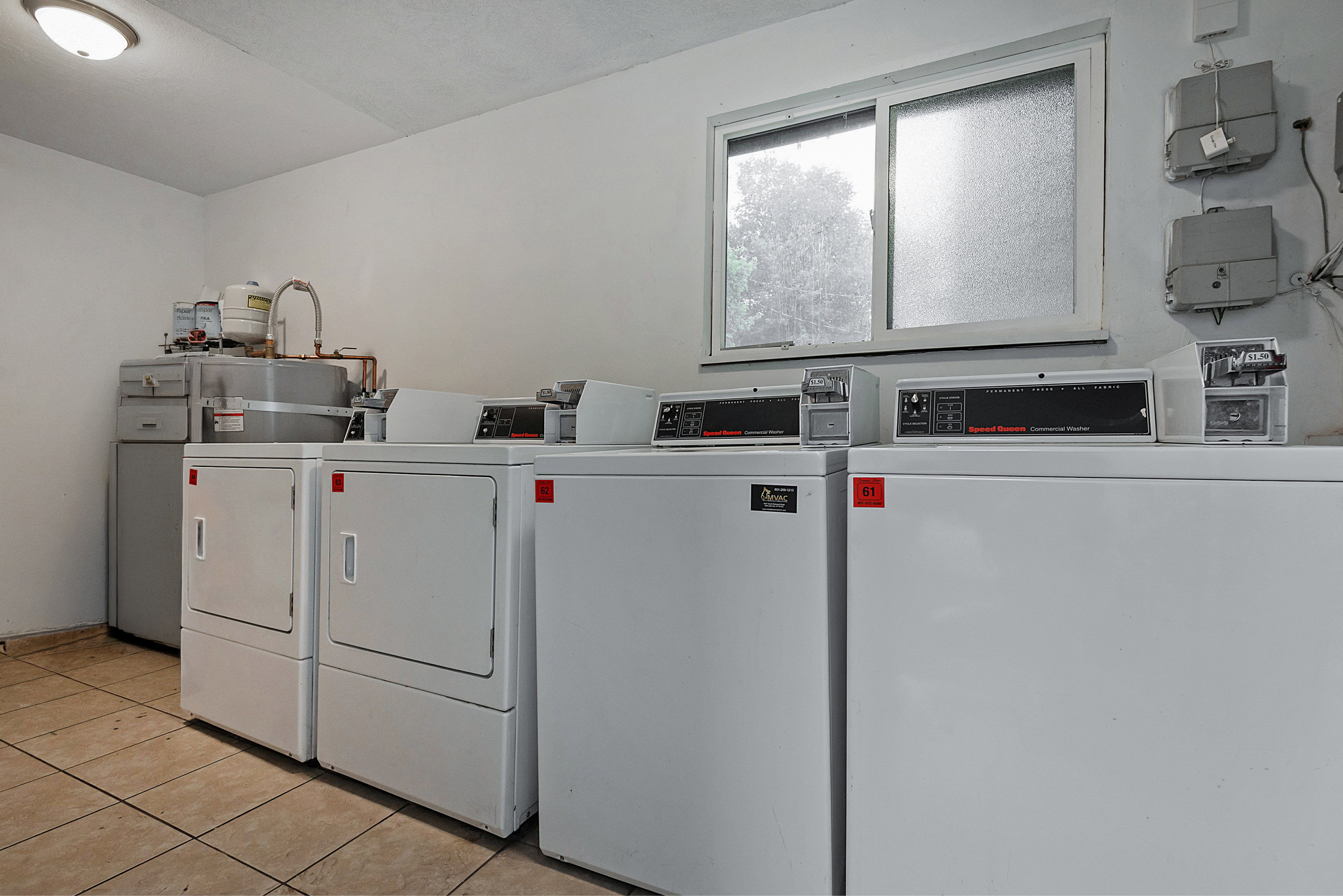 Dedicated laundry area featuring multiple commercial-grade washers and dryers