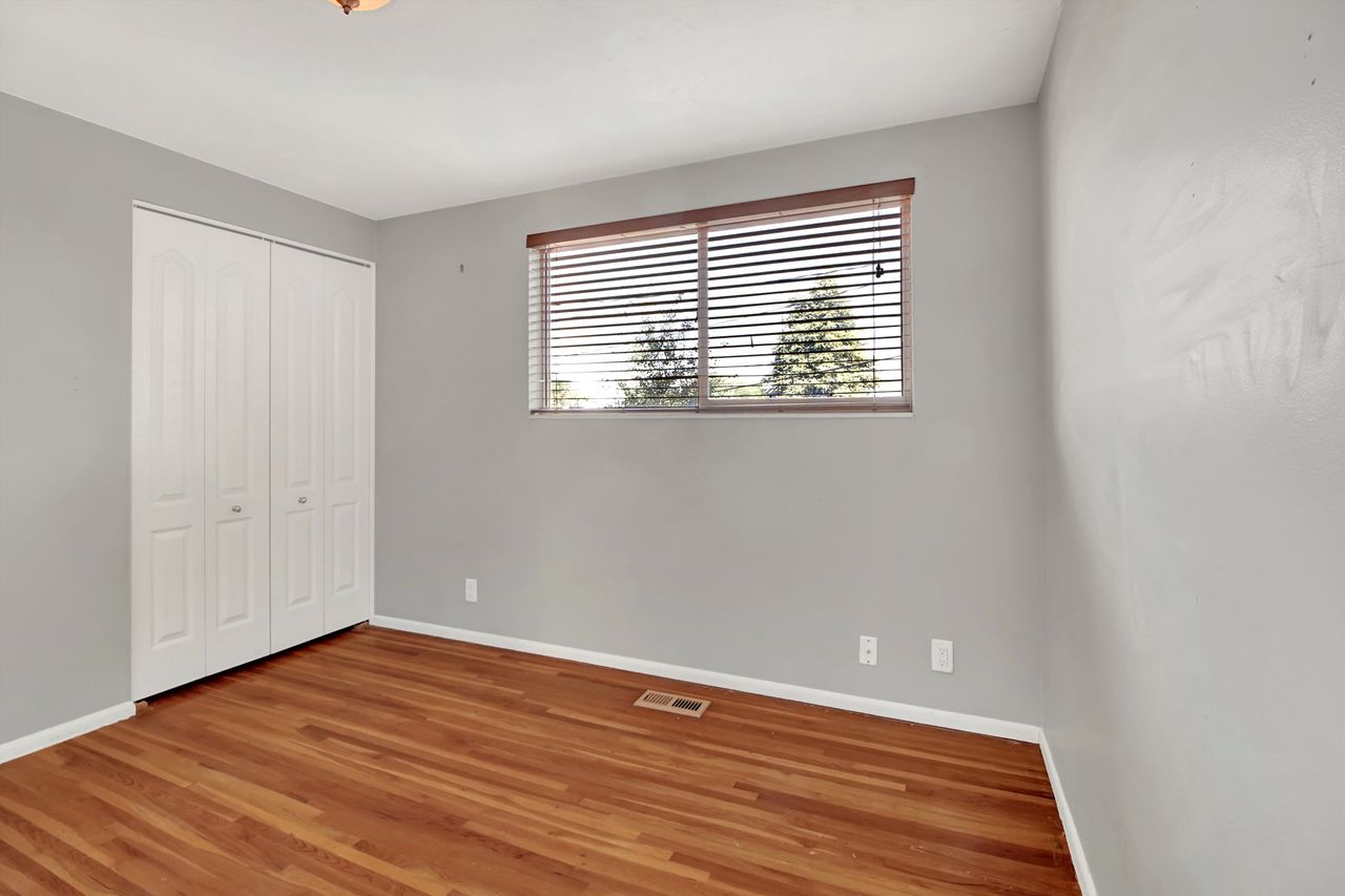 Room featuring warm wood-finish flooring, light grey painted walls, and white baseboards