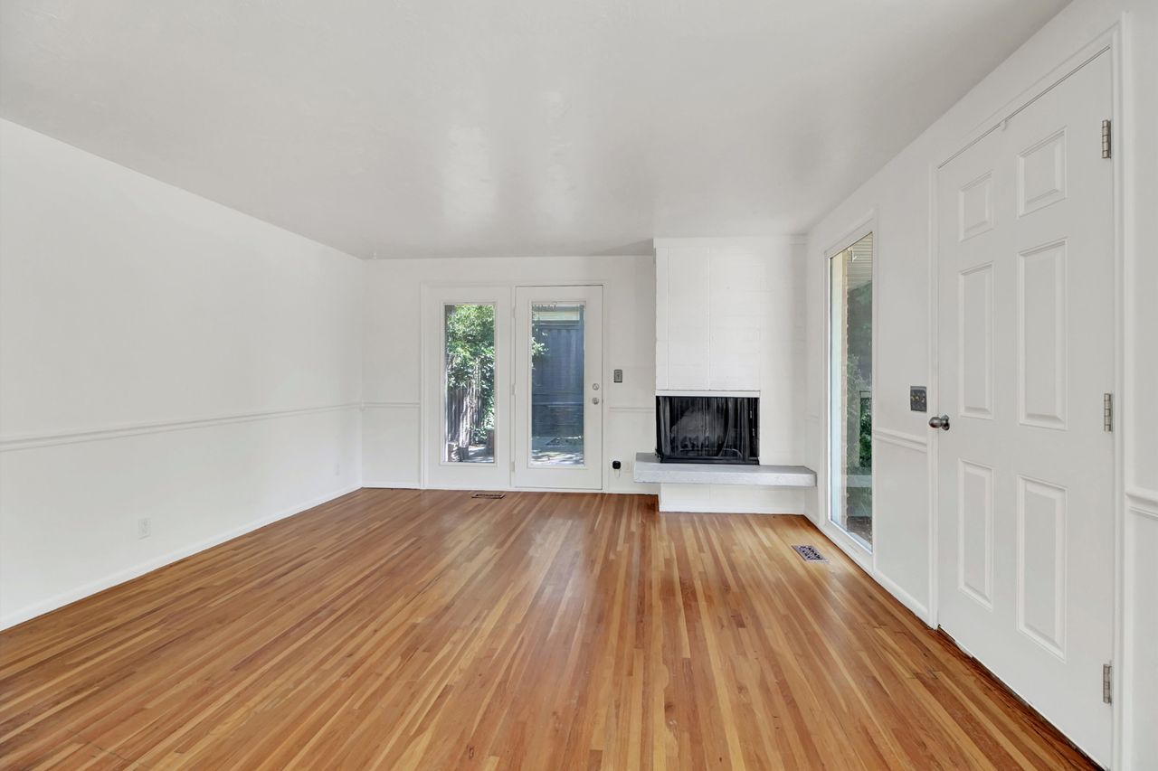 Hardwood flooring complemented by white walls and a fireplace.