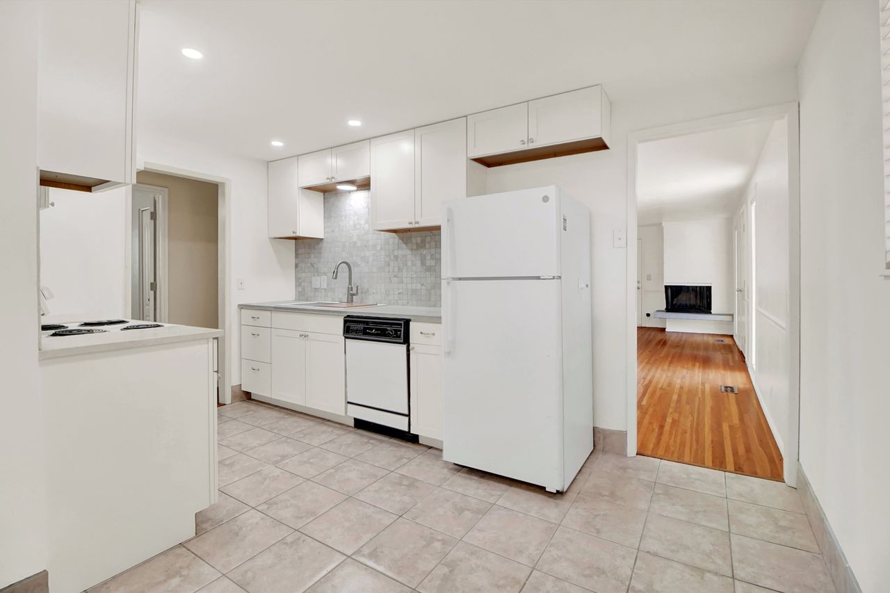 Kitchen featuring white cabinetry, tile flooring, stone-look backsplash, stainless steel sink with a gooseneck faucet, and recessed lighting