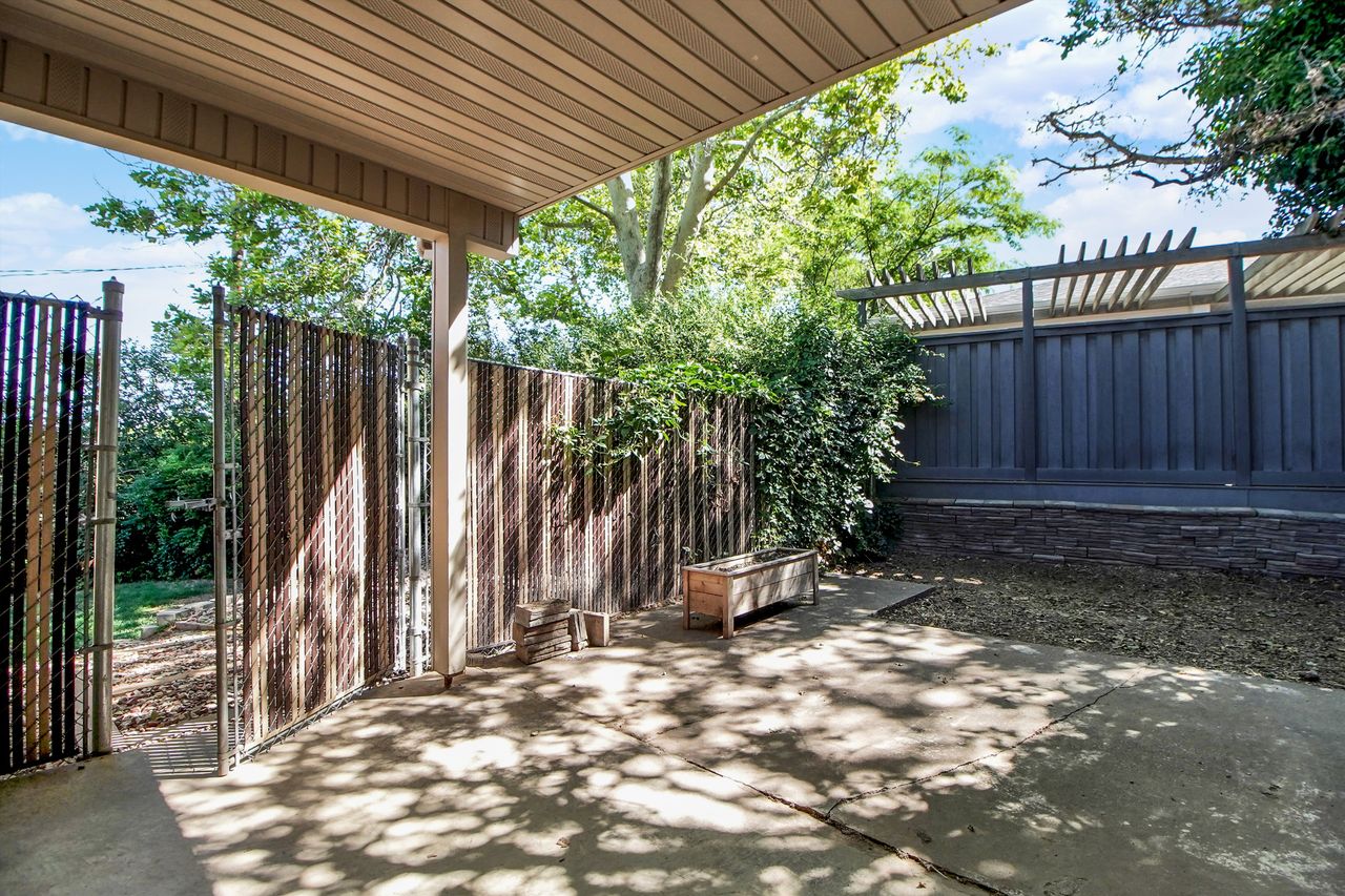Covered patio with a concrete surface, featuring a slatted ceiling and support column