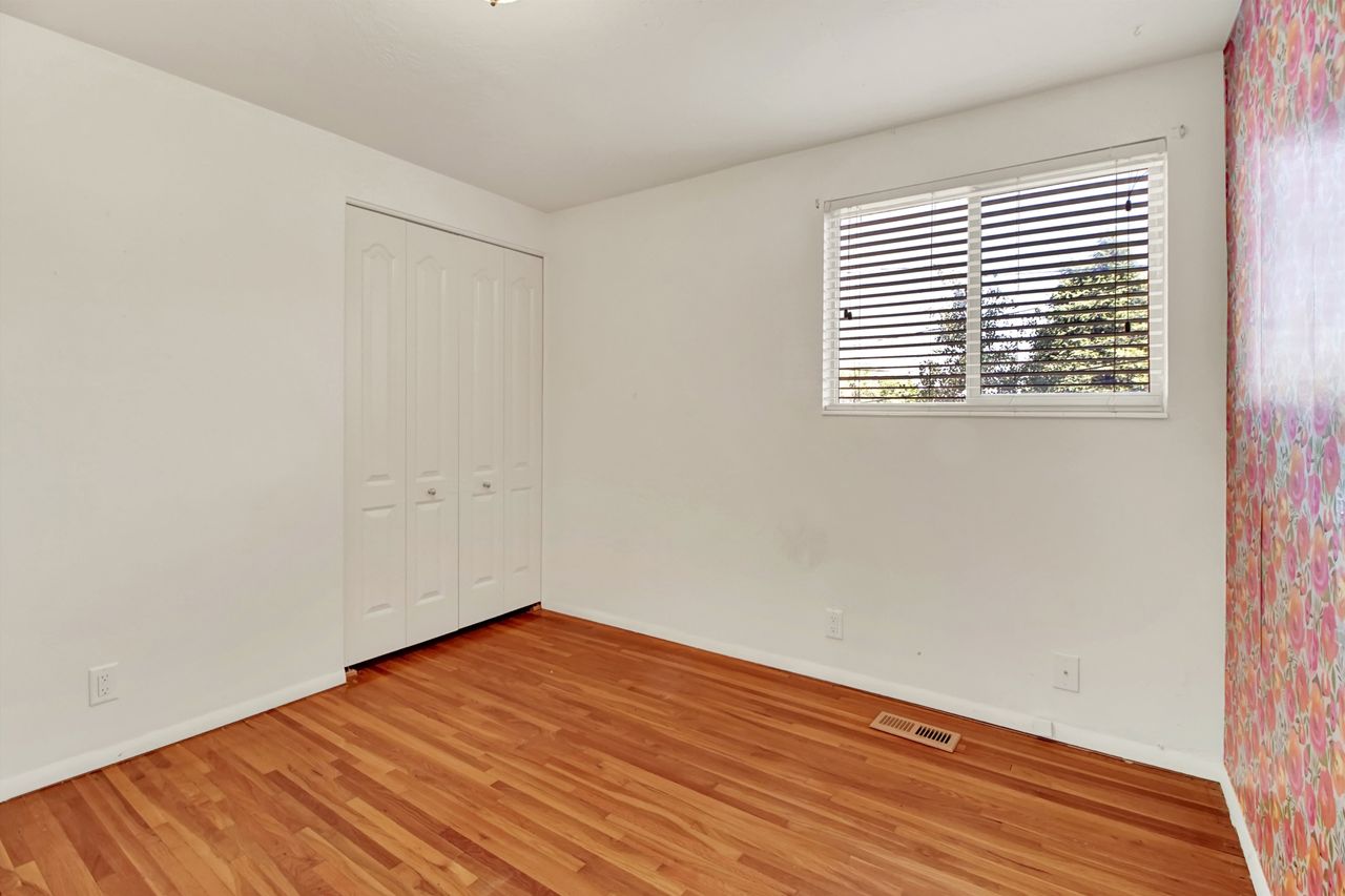 Main level Bedroom  featuring wood-finish flooring, white walls, and a window with horizontal blinds