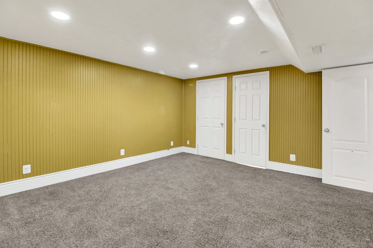 Spacious room featuring textured wall paneling, recessed lighting, white trim, and plush carpeting,