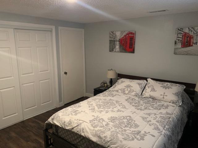 Sleeping area featuring wood-finish flooring, two-panel bifold closet doors, a single-panel interior door, light gray wall paint, and a ceiling-mounted light fixture