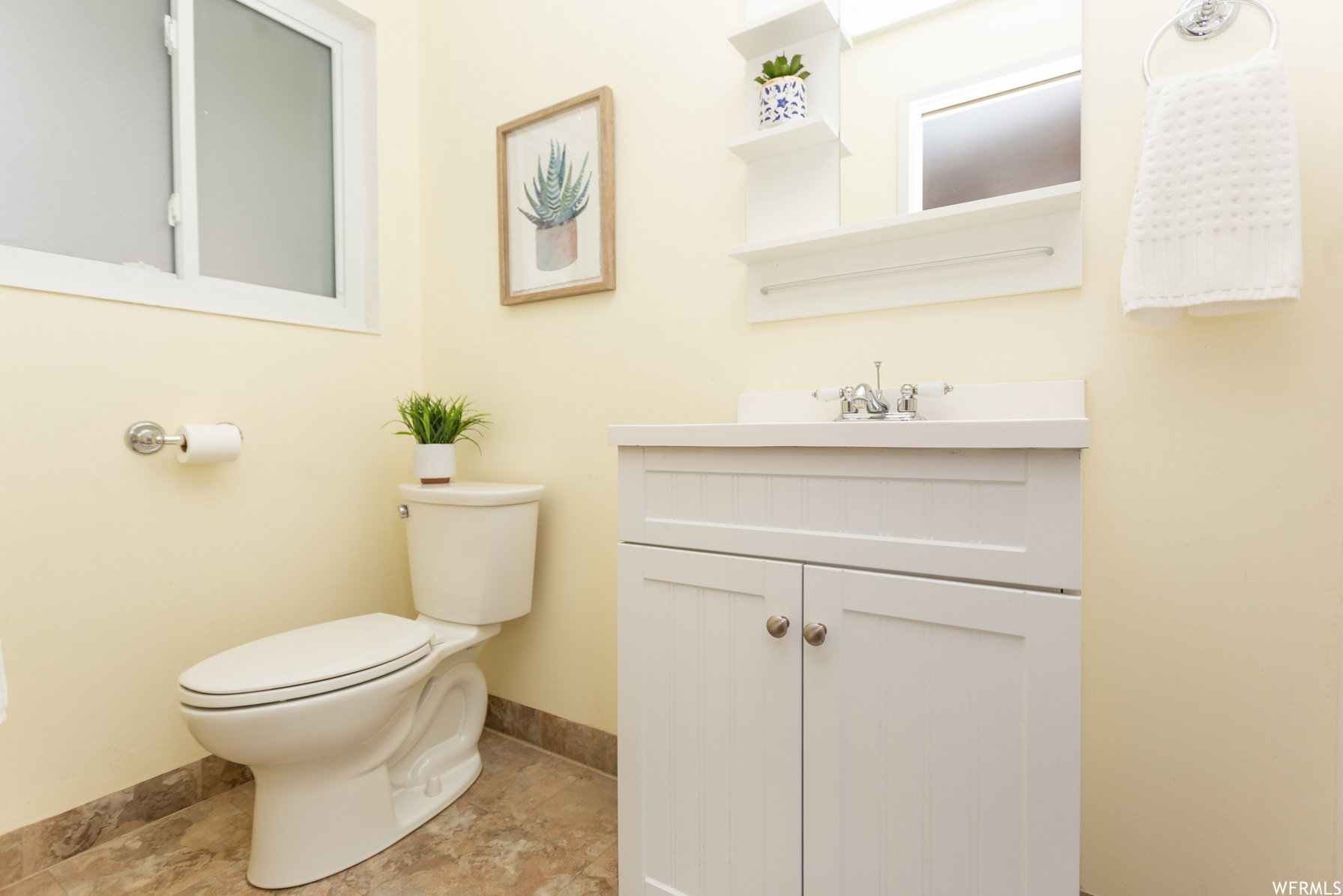 en suite bathroom. White vanity with brushed nickel hardware, a single basin sink, and a chrome faucet