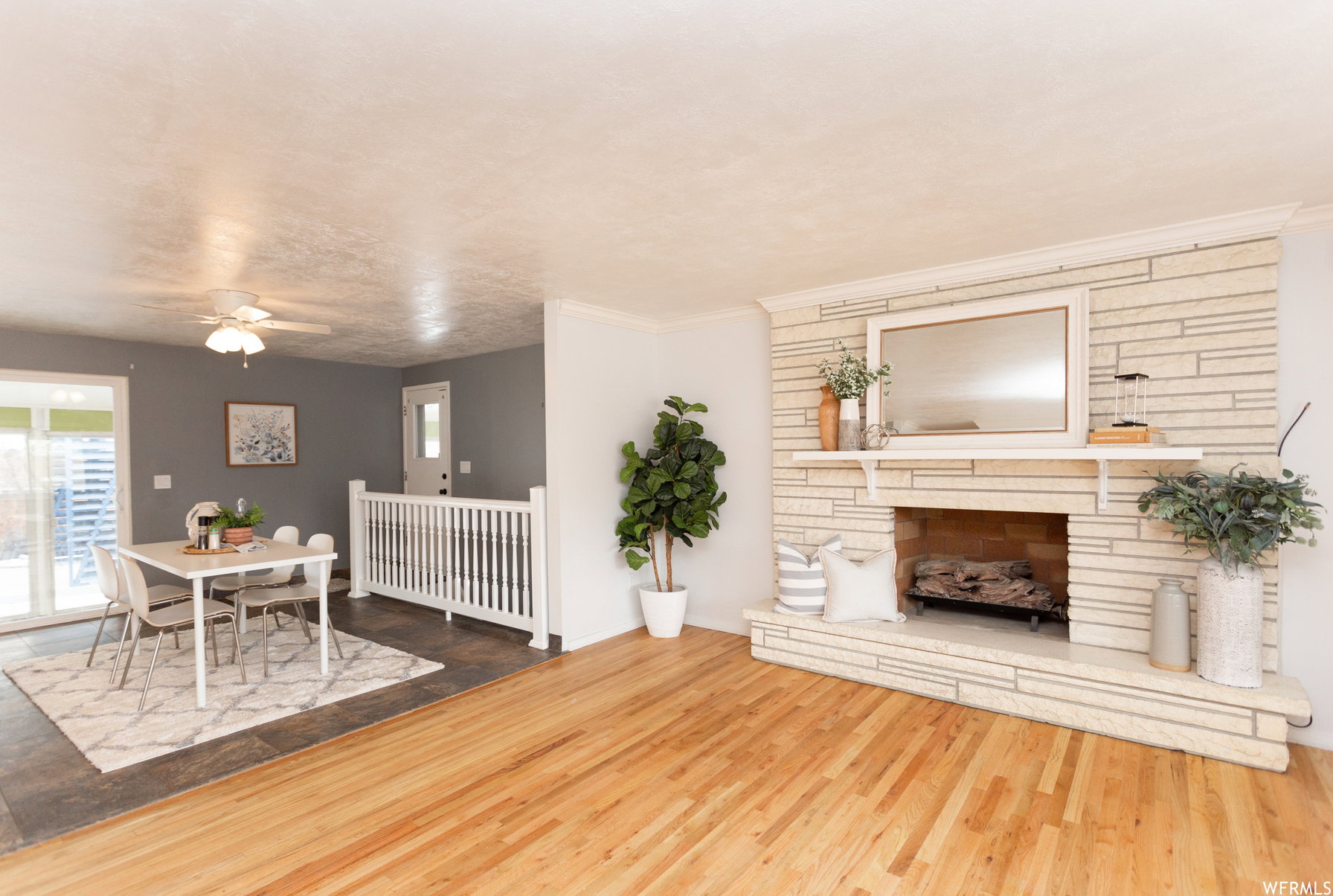 Spacious living area featuring wood-finish flooring and a stone-clad fireplace with a mantel shelf