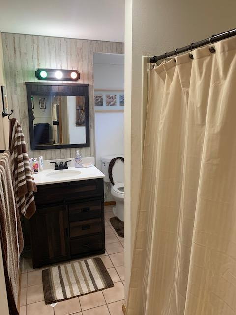 Bathroom featuring a dark wood-finish vanity with a white countertop and integrated sink, a framed mirror, and a three-bulb vanity light fixture