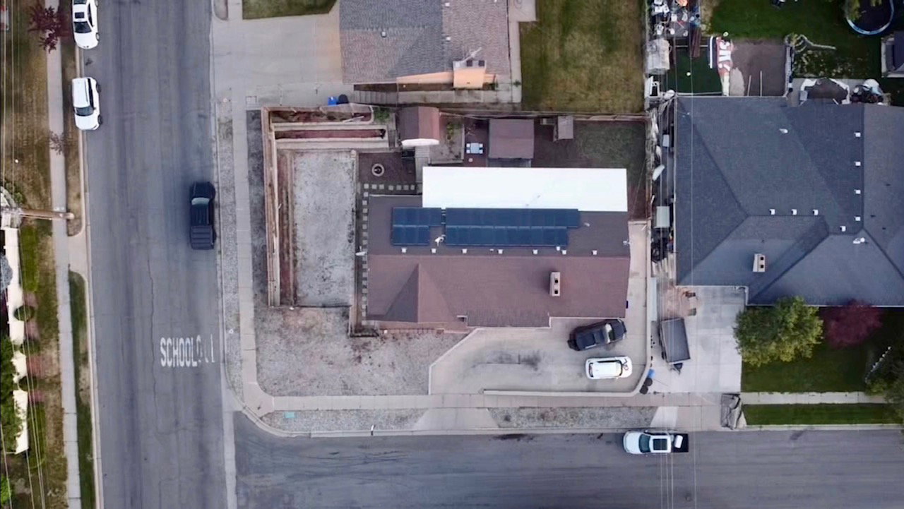 Property featuring solar panel installation, a detached shed, paved driveway, and an adjacent cleared lot
