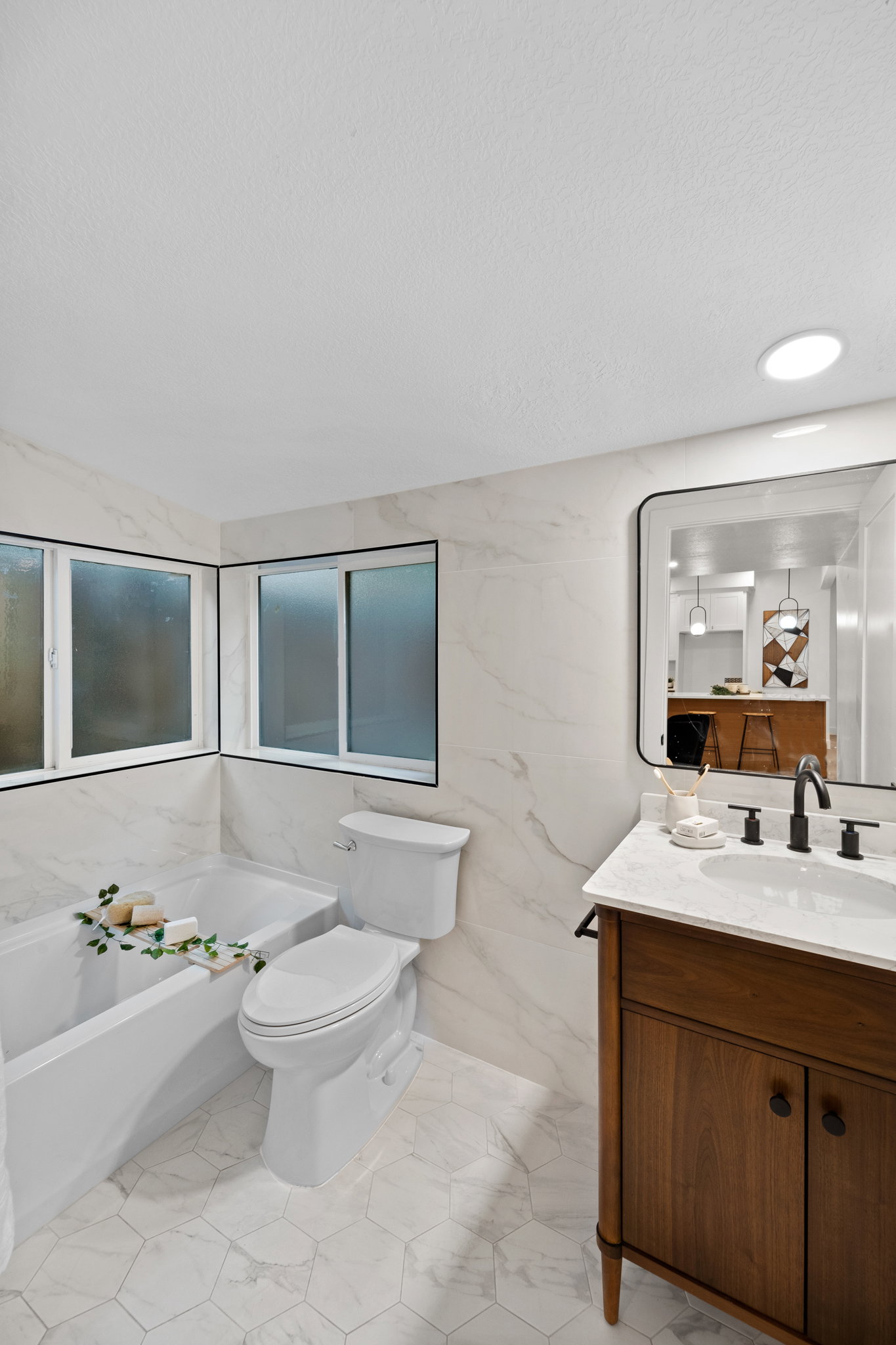 Bathroom featuring a white bathtub, white toilet, and wood-finish vanity with a white countertop