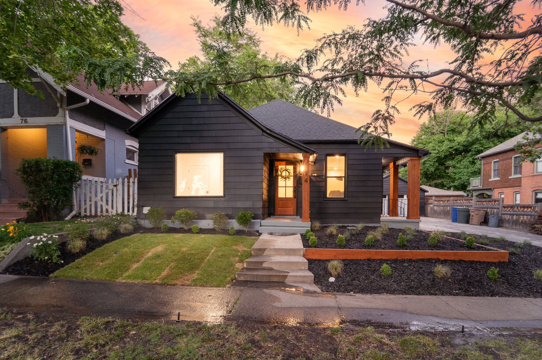 Modern black exterior with natural wood porch columns and front door