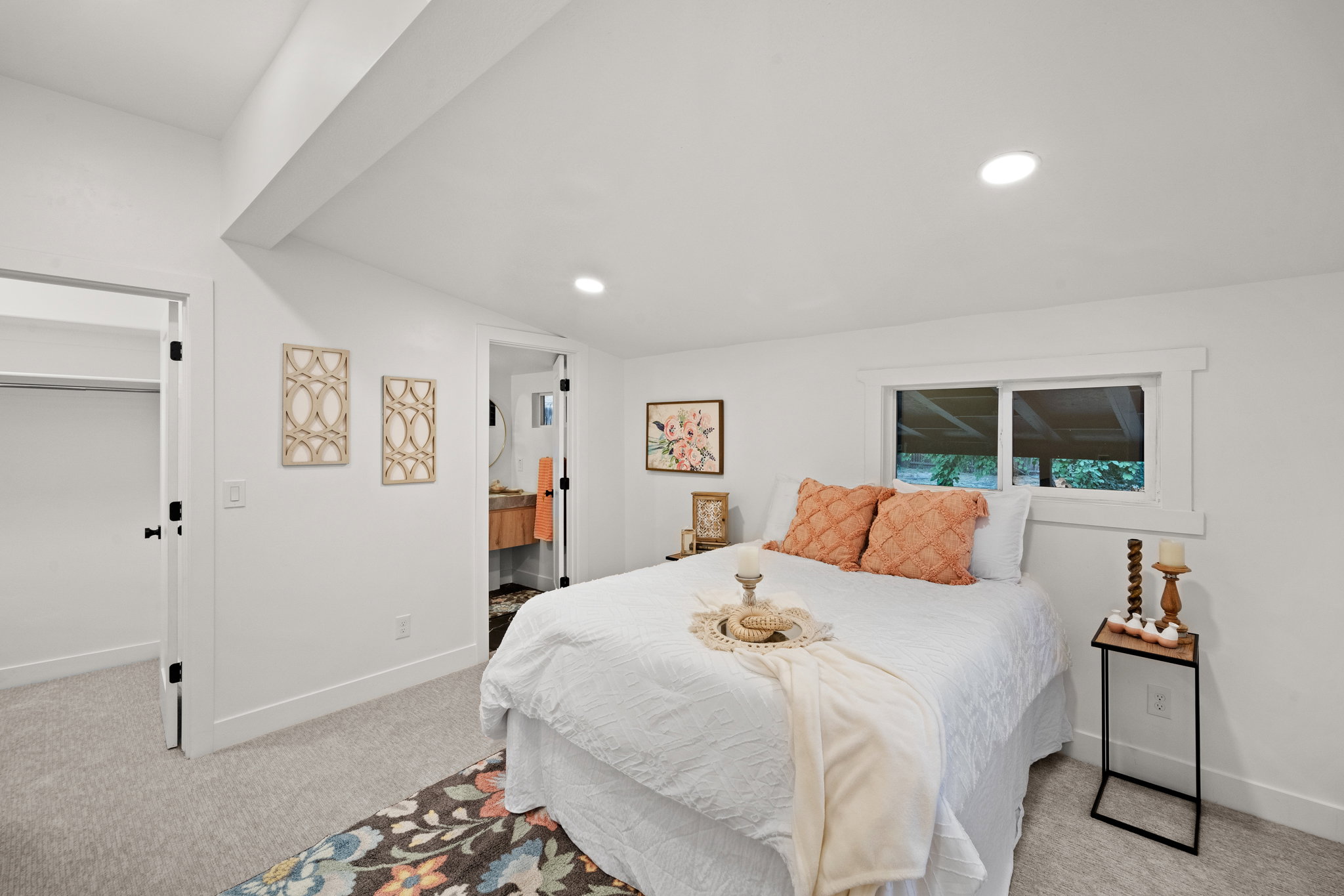 Recessed lighting illuminates this room featuring white walls, light-colored carpeting, and a window with white trim