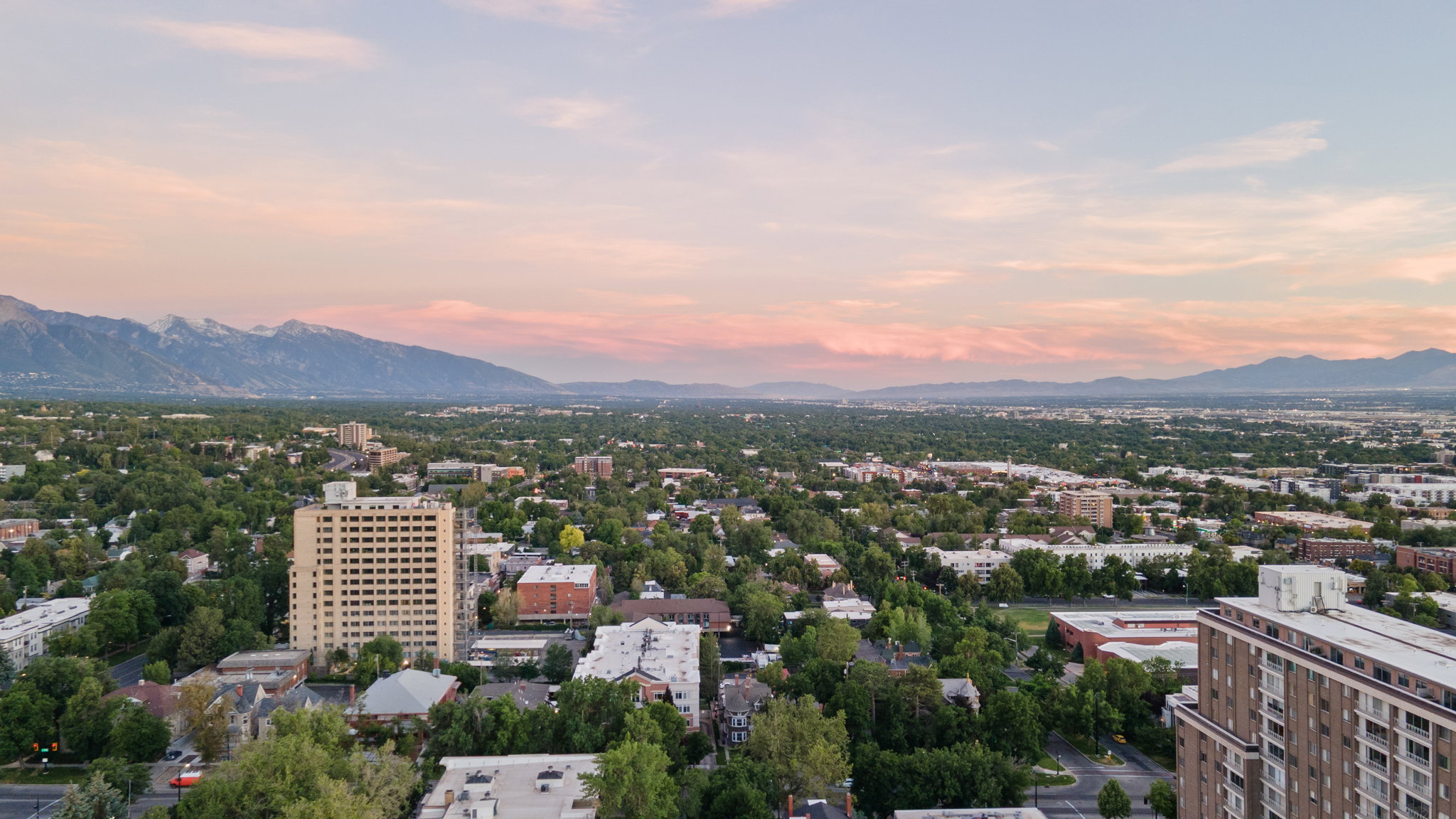 Expansive cityscape with distant mountains under a dramatic sunset sky
