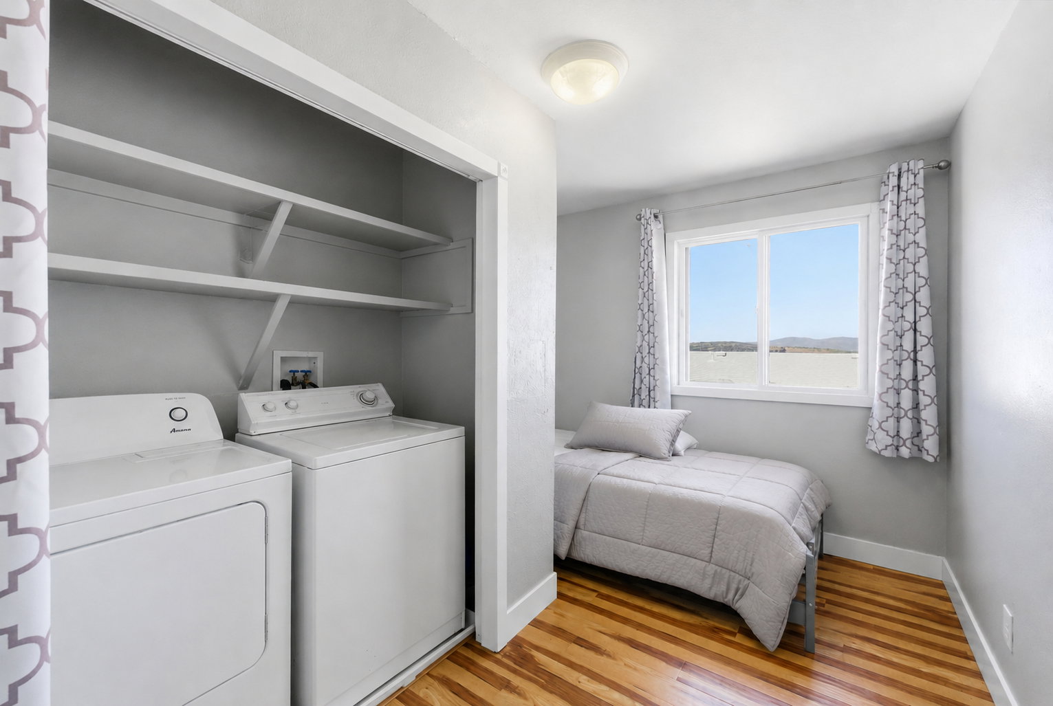 Compact laundry area featuring a washer and dryer, complemented by overhead shelving for storage