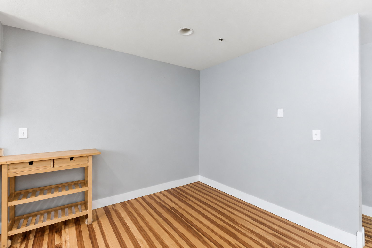 Room featuring light gray painted walls, white trim, wood-finish flooring, and a recessed ceiling light