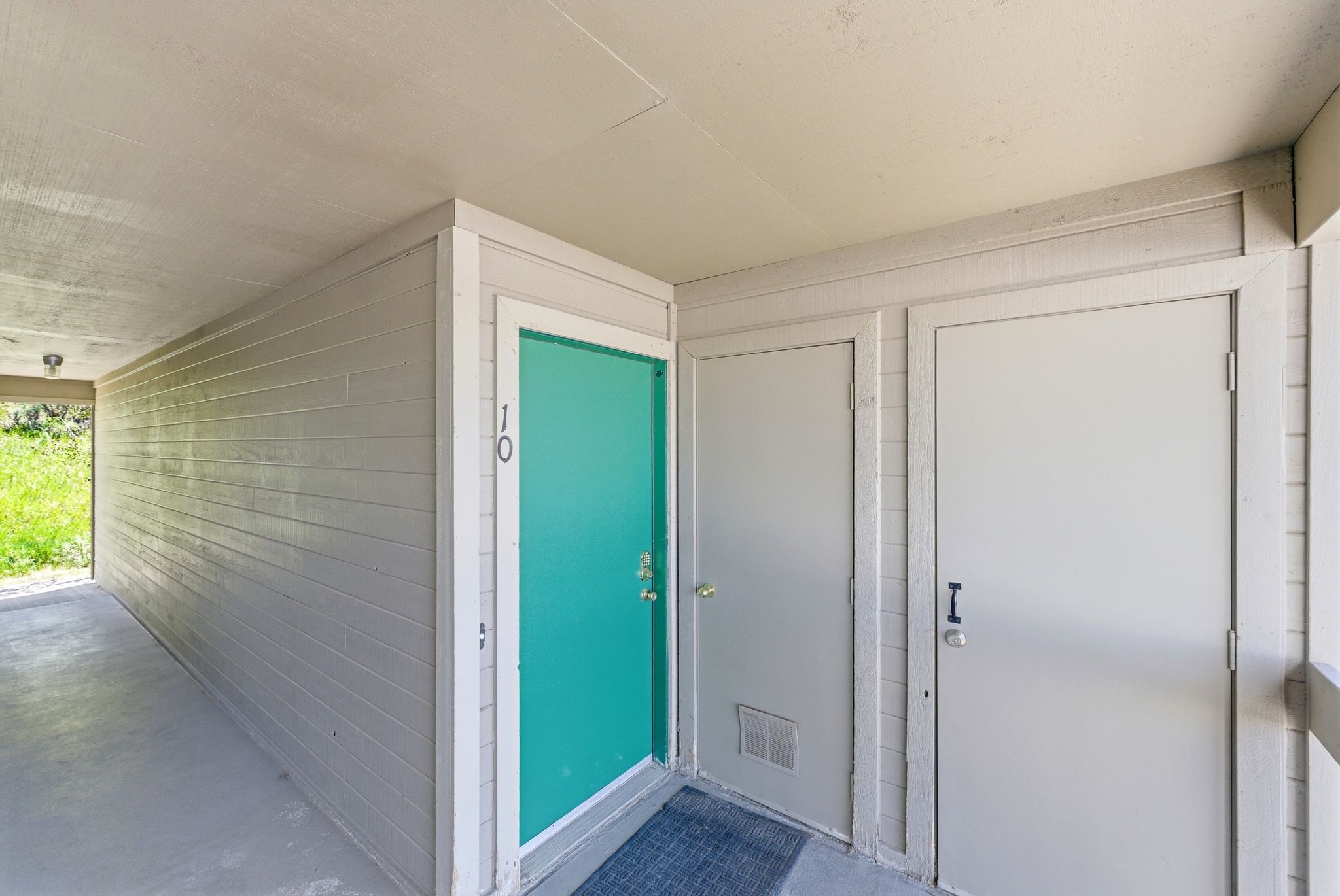 Teal entry door with white trim, flanked by two additional light gray doors