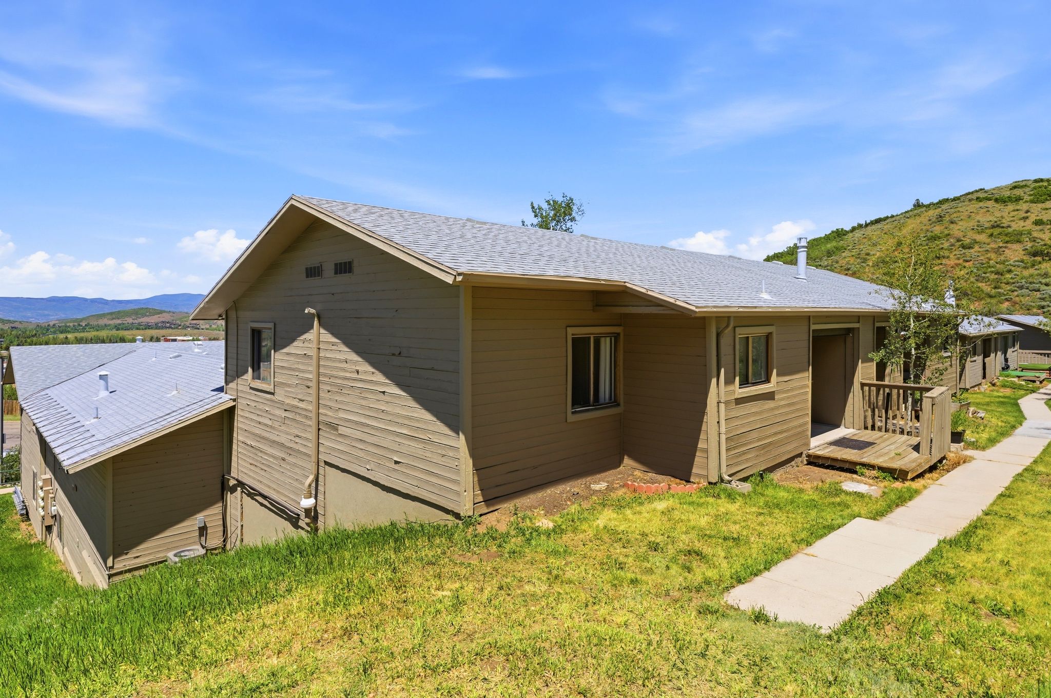 Horizontal siding exterior with a shingle roof and a wooden deck entry