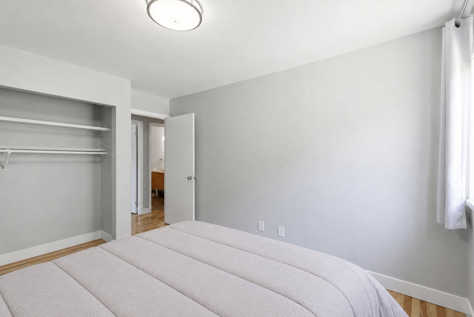 Bedroom featuring light gray walls, wood-finish flooring, and a flush-mount ceiling light
