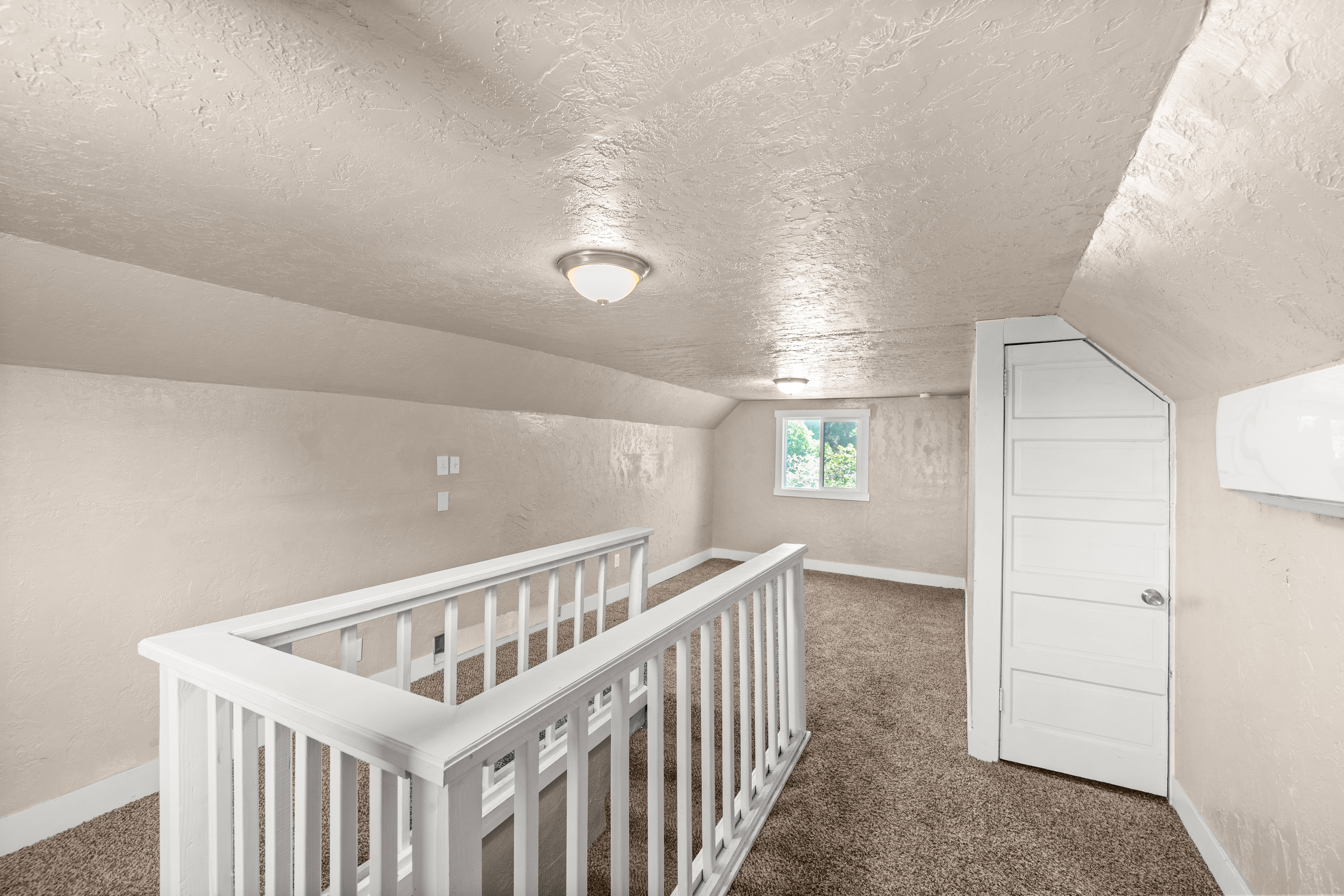 Carpeted upper level featuring sloped ceilings, white painted railing, and an integrated air conditioning unit