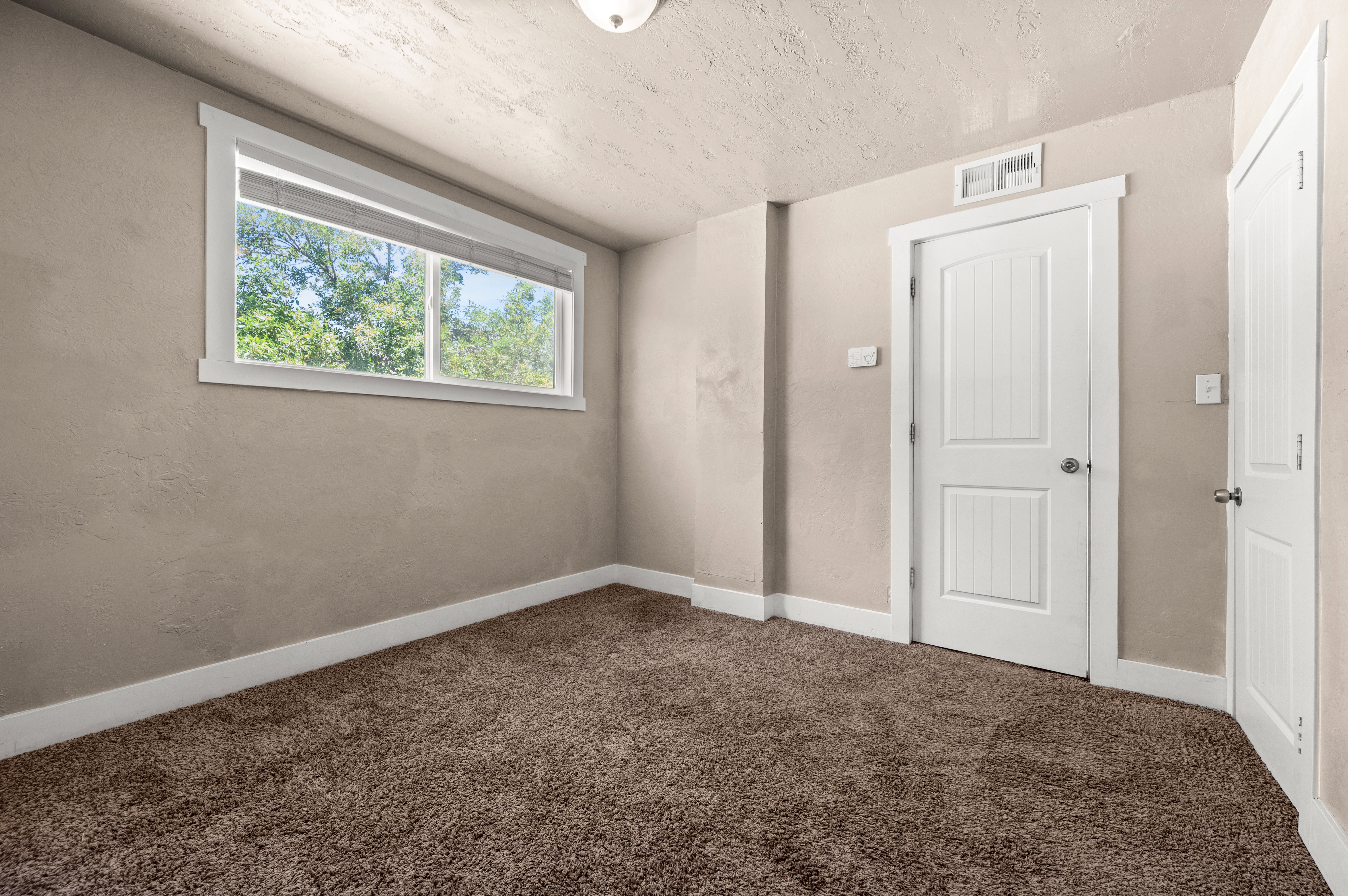 Neutral tone walls featuring white baseboards, a white-framed window, and two white panel doors
