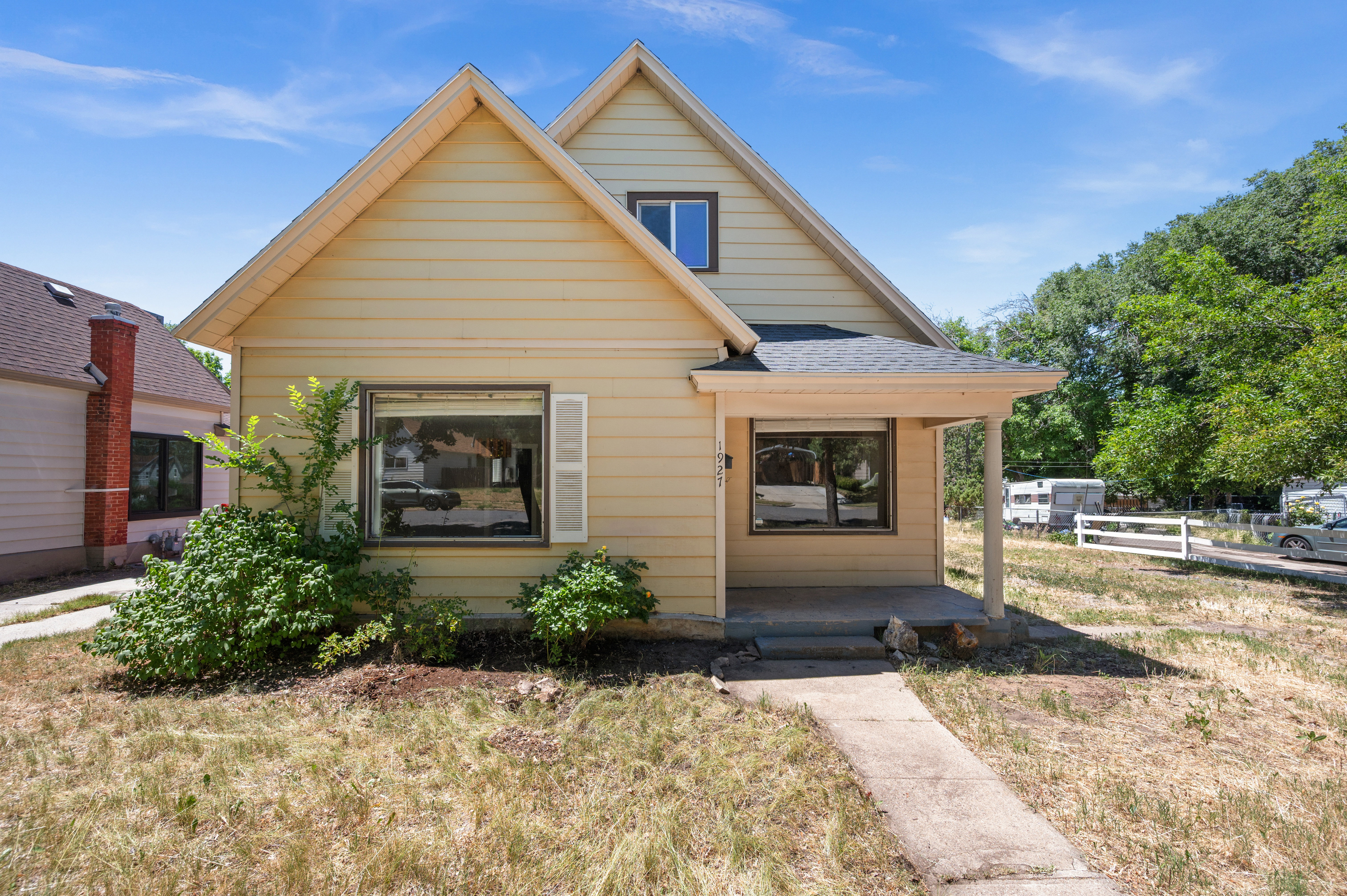 Gable roofline residence with yellow siding and white window shutters