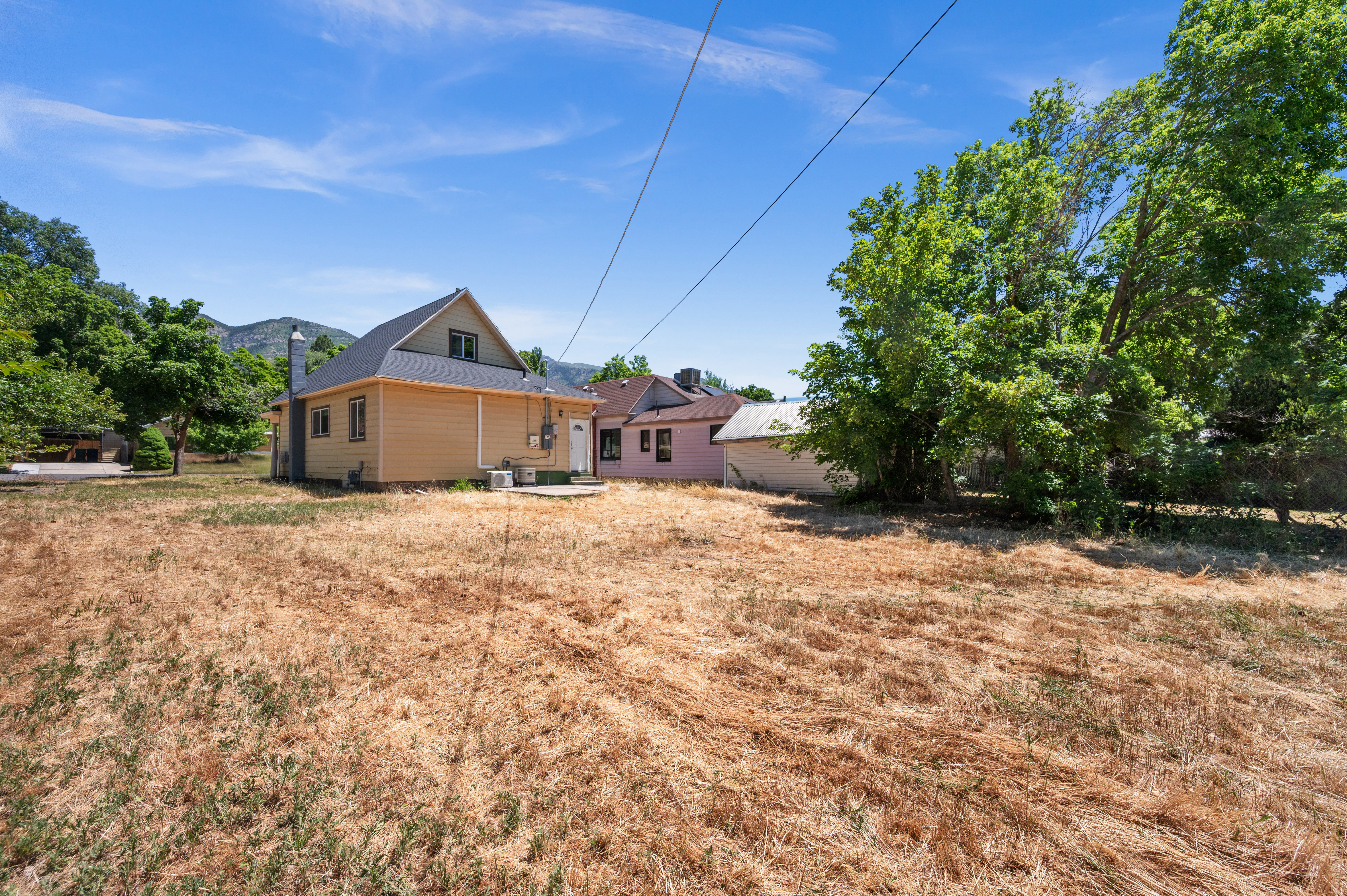 Expansive grassy yard with mature trees and mountain backdrop