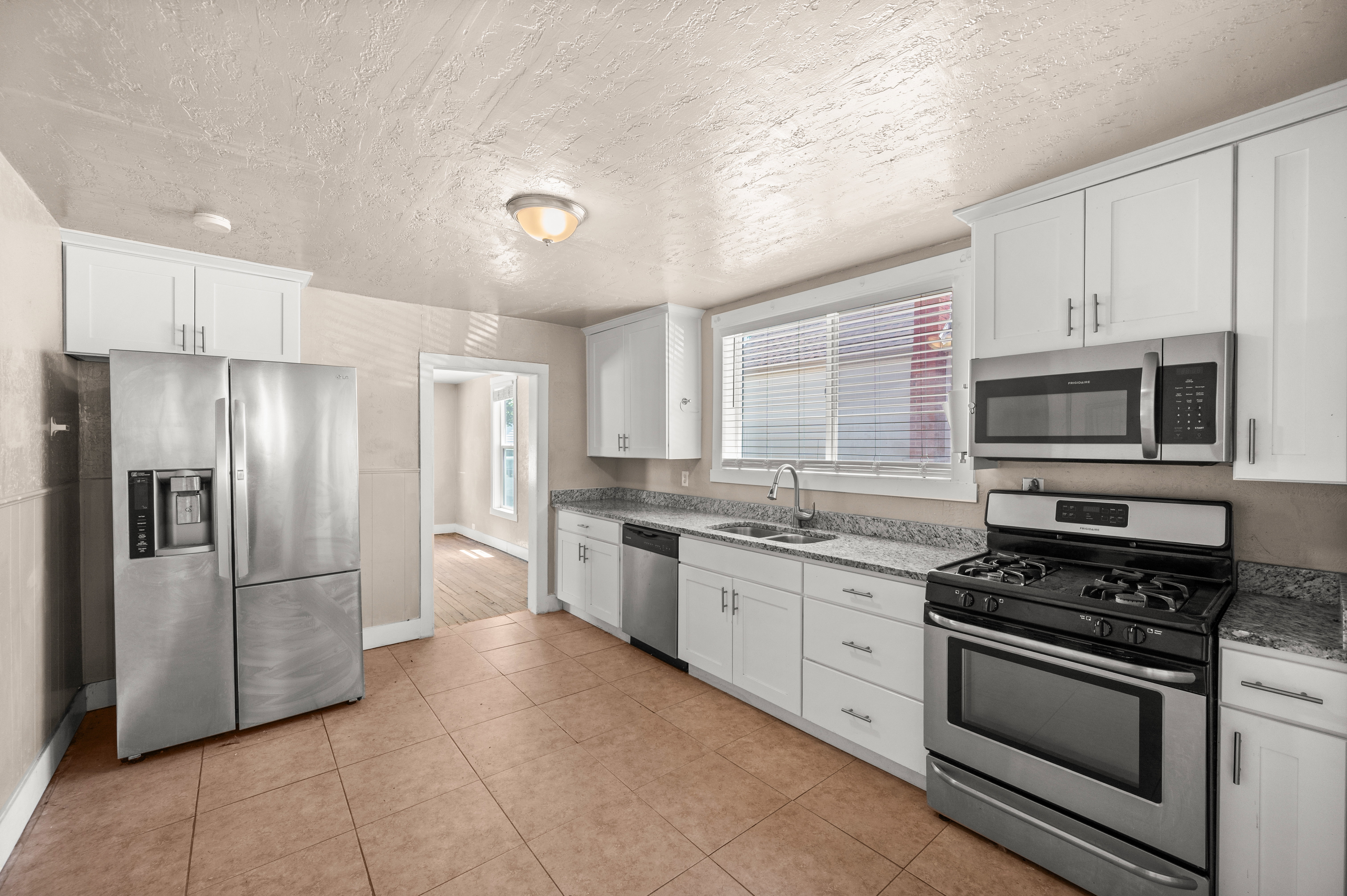 Kitchen featuring white cabinetry, stone-finish countertops, stainless steel appliances, and tile flooring