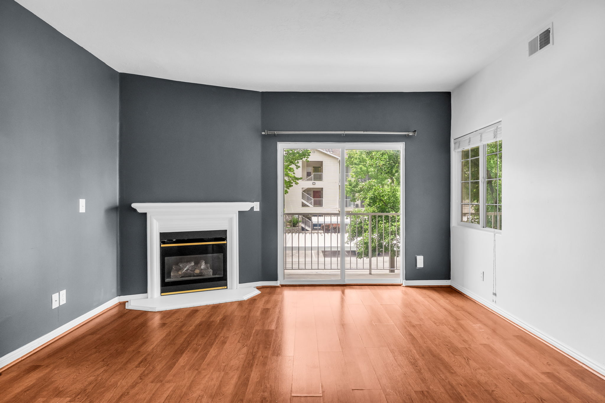 Living space featuring wood-finish flooring, a white mantel fireplace, and a sliding glass door opening to an exterior balcony