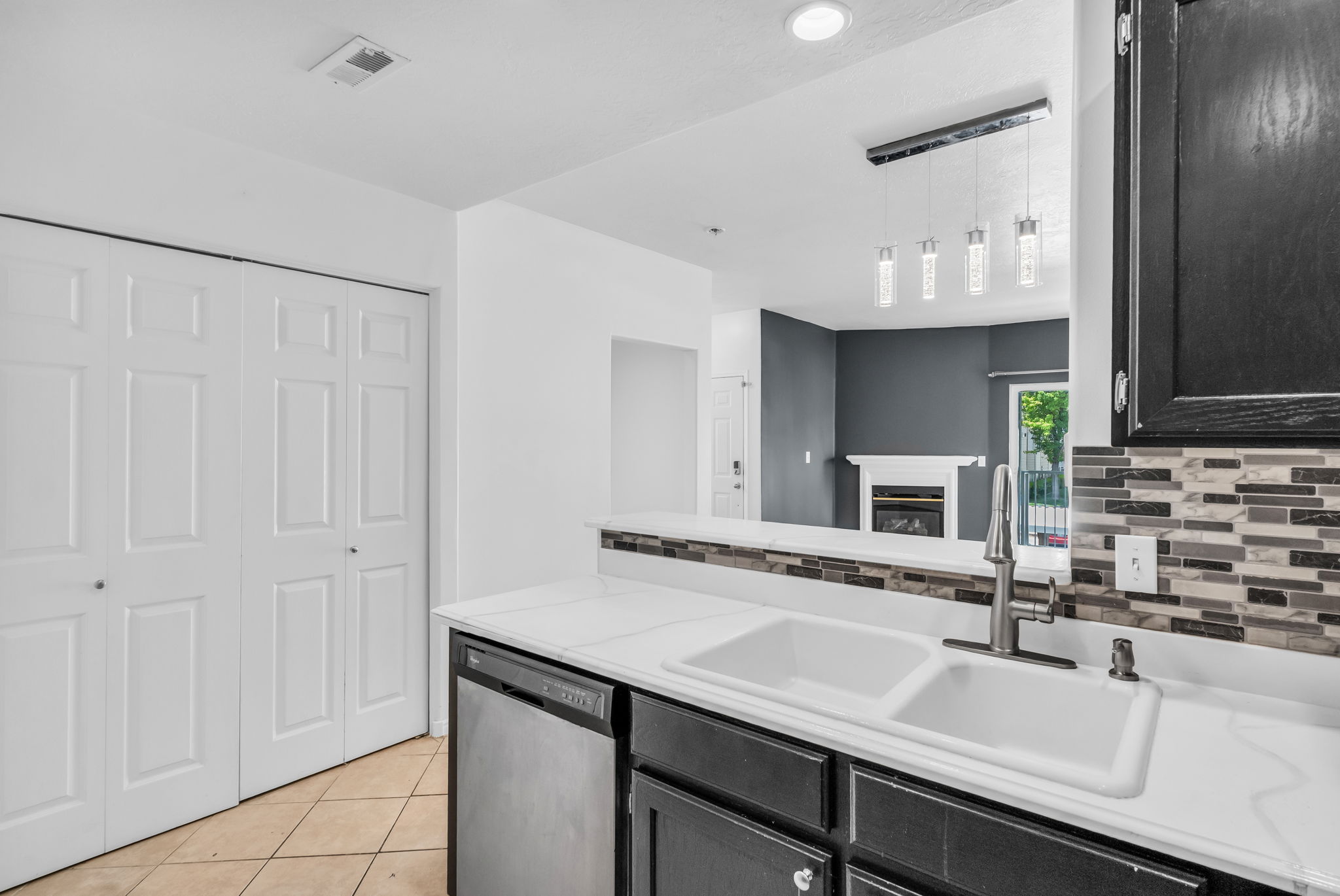 Kitchen featuring a dual-basin sink with a gooseneck faucet, white countertops, and dark cabinetry
