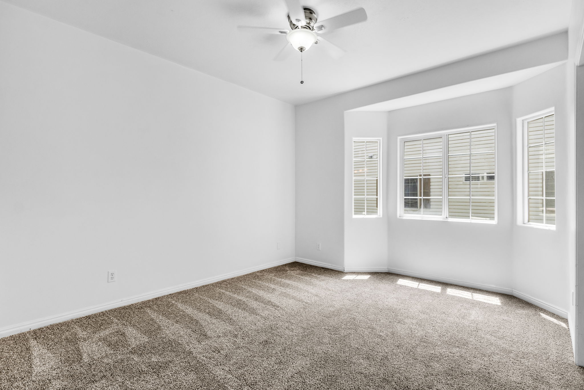 Bedroom featuring plush carpeting, a ceiling fan with light fixture, and a bay window with multiple panes and horizontal blinds