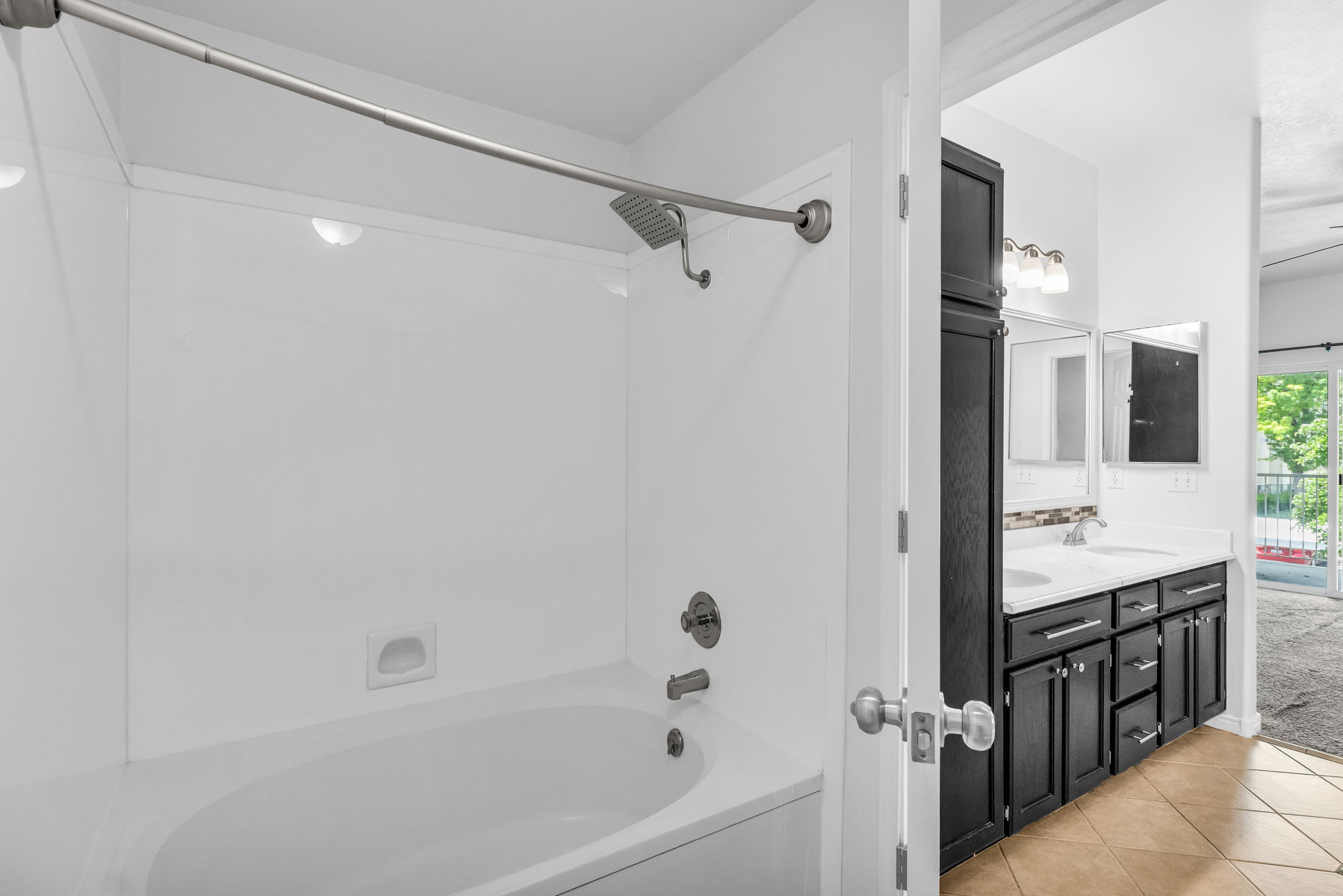 Bathtub with integrated shower, featuring a white surround, and brushed nickel fixtures