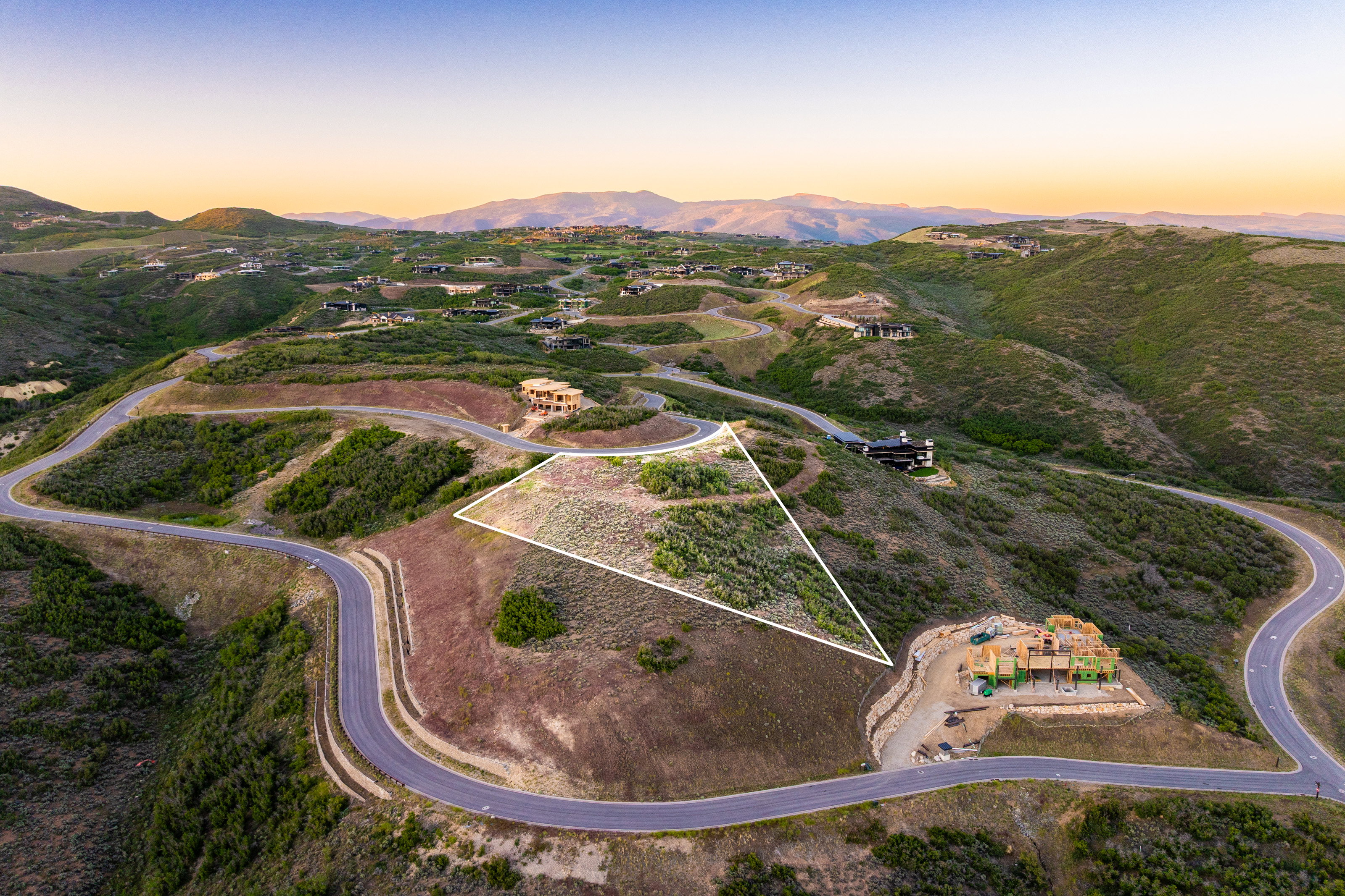 Expansive mountain property featuring a defined building envelope, winding roadways, and surrounding natural vegetation