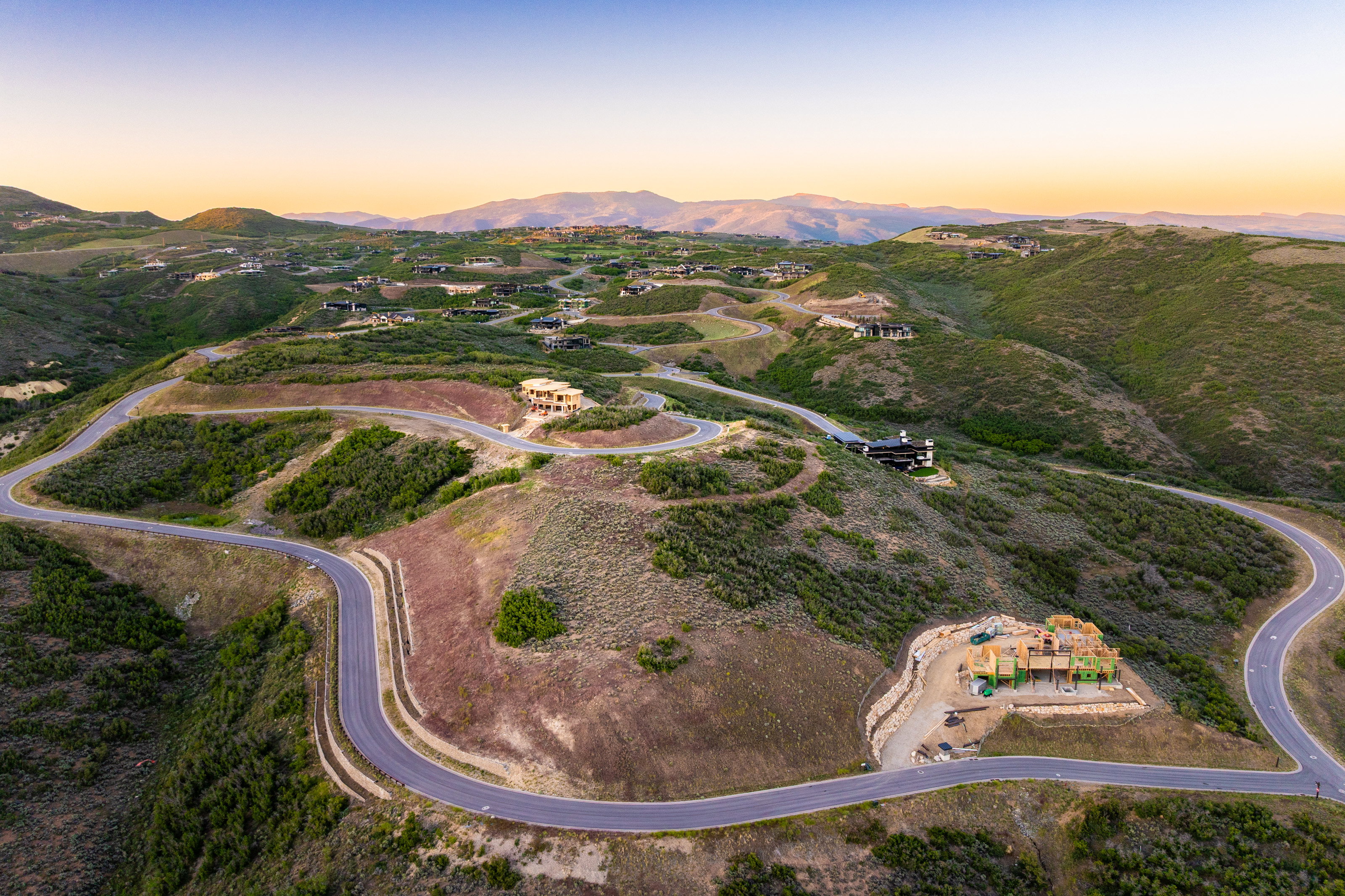 Hillside community featuring paved roads, undulating terrain, and distant mountain ranges