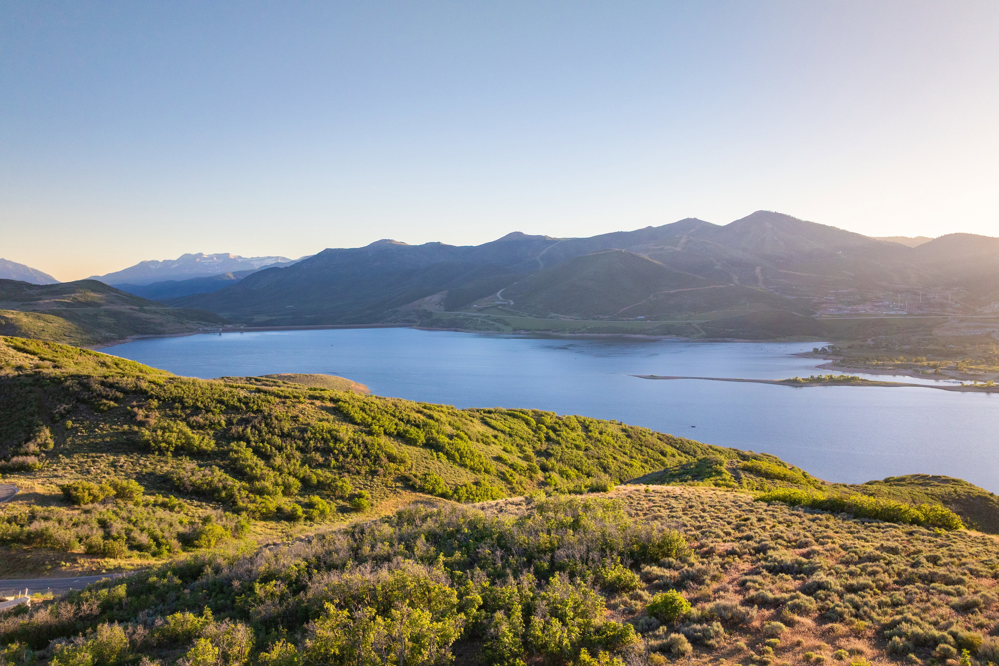 Expansive body of water framed by rolling hillsides and distant mountains