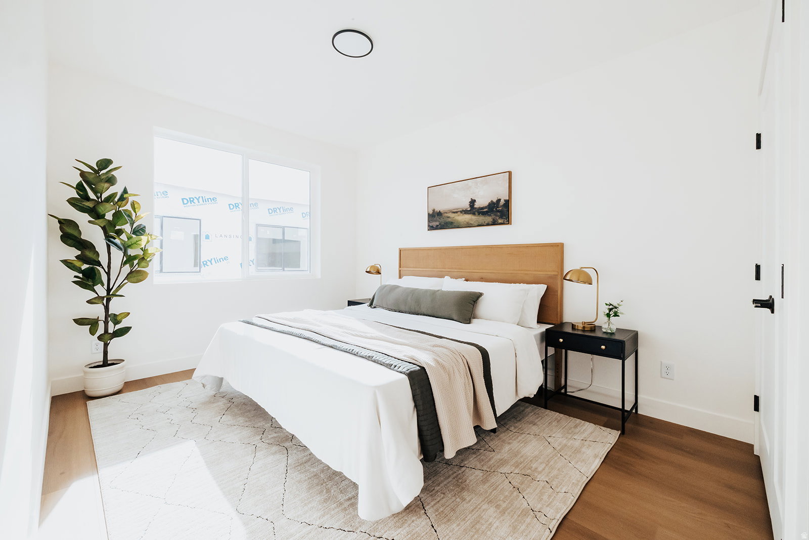 Bedroom featuring light wood-finish flooring, white walls, and a large window