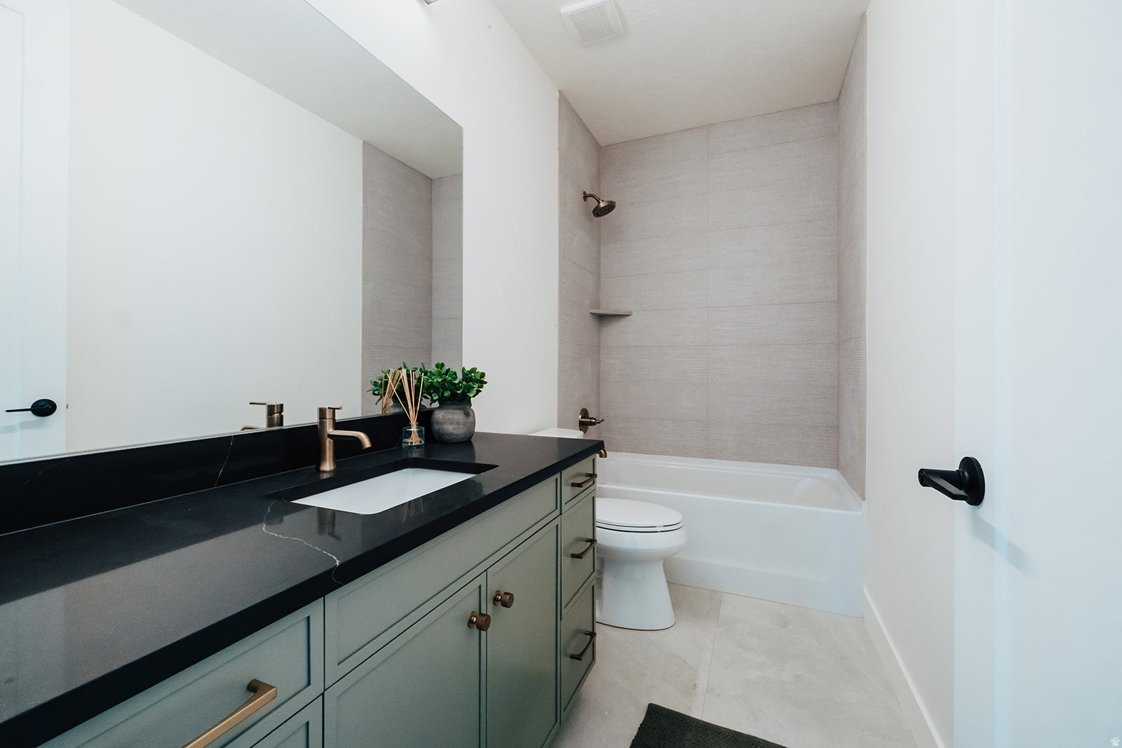 Modern bathroom featuring a mint green vanity with a dark countertop and a rectangular undermount sink