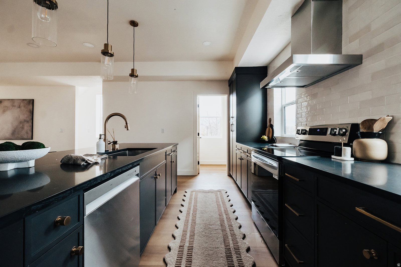 Modern kitchen featuring dark cabinetry, dark countertops, and stainless steel appliances