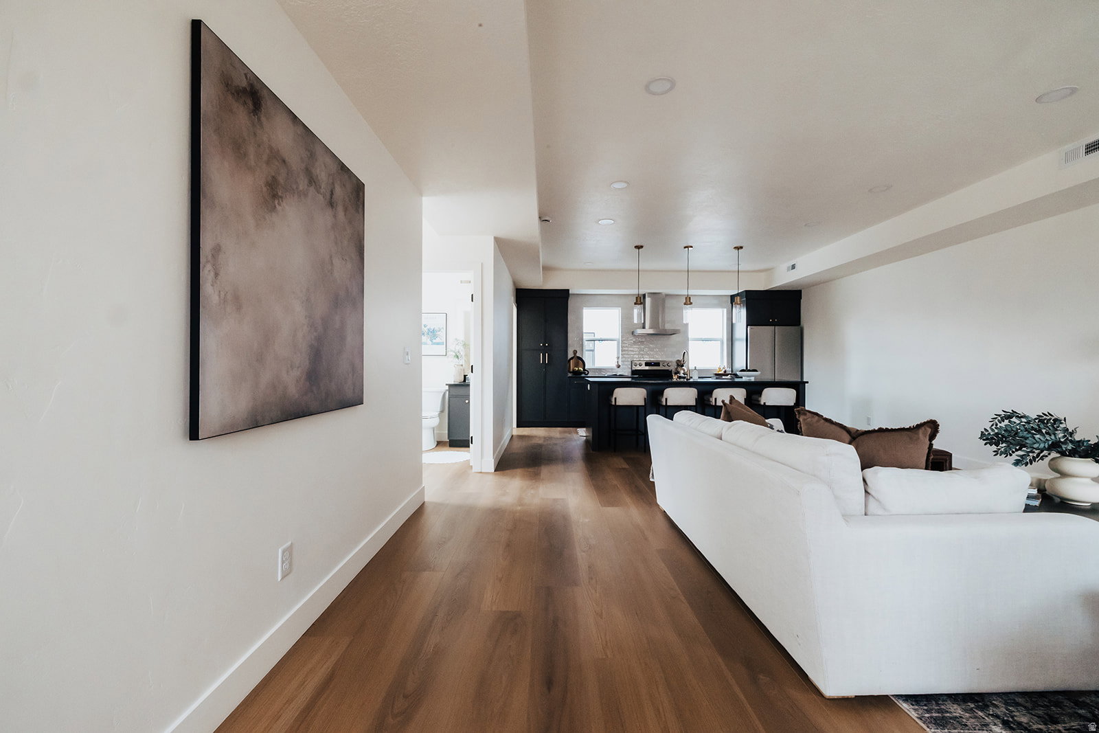 Open-concept living space featuring wood-finish flooring, recessed lighting, and a modern kitchen